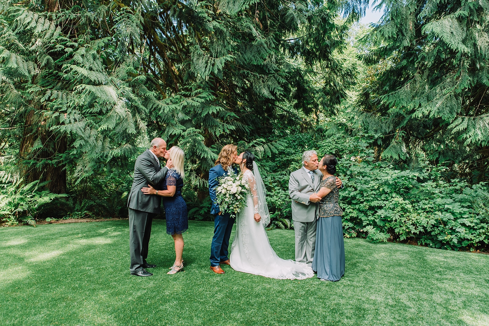 bride and groom with parents kissing