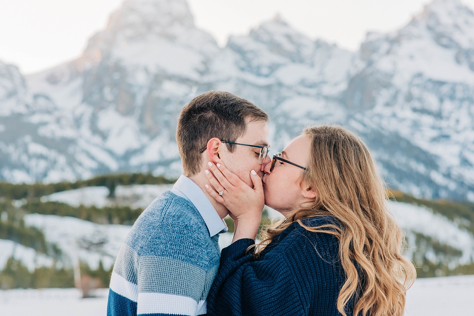 newly engaged couple kissing during winter engagement session 