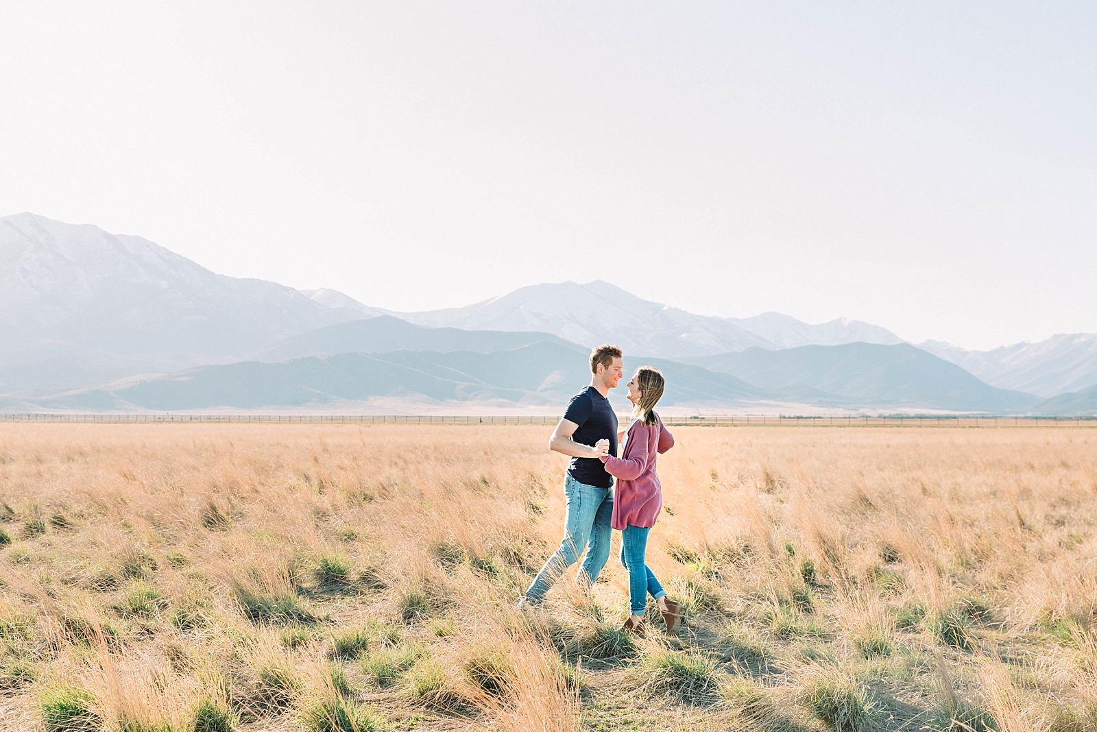 Young couple walking through field during couples session