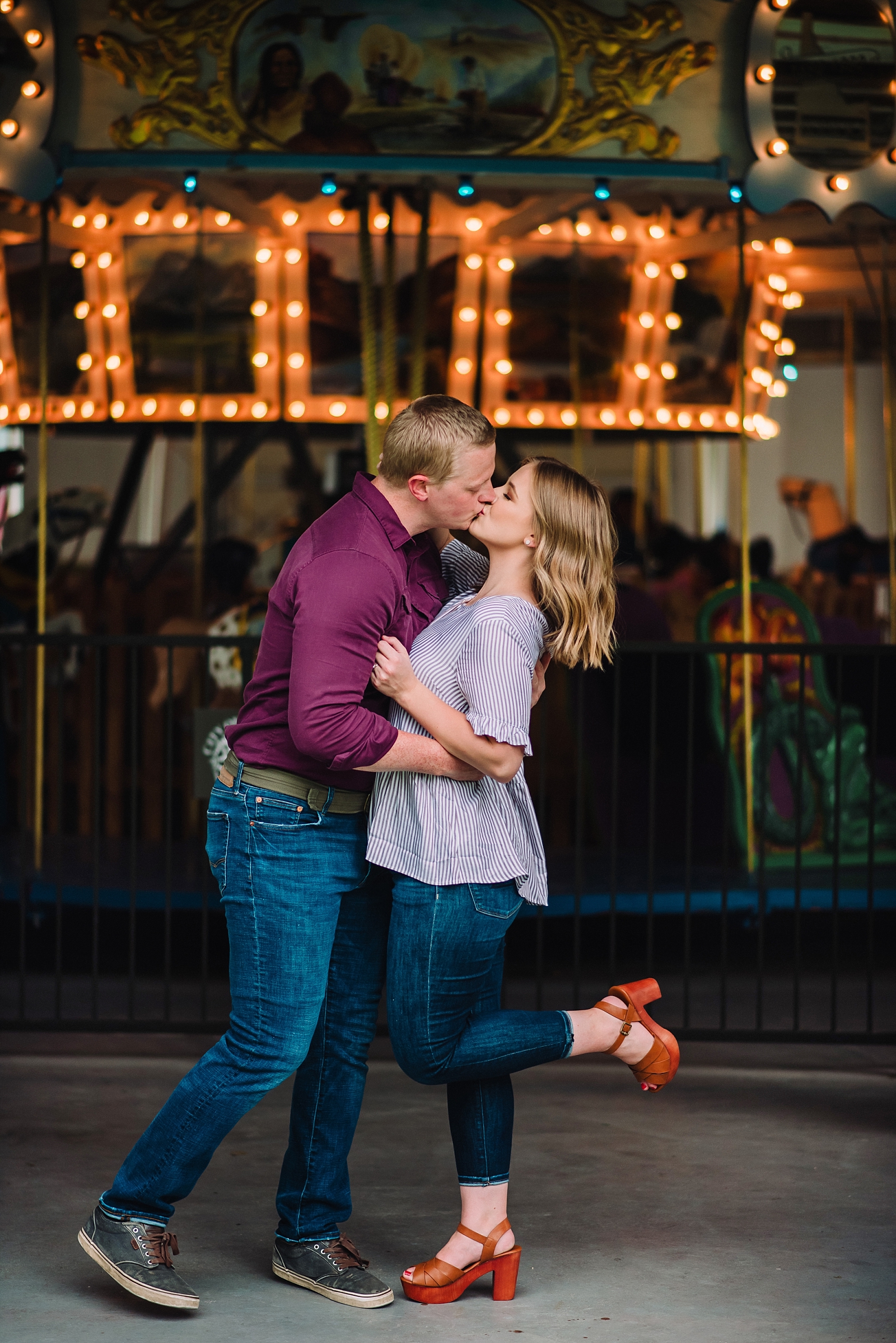 man and woman kissing in front of rexburg carousel