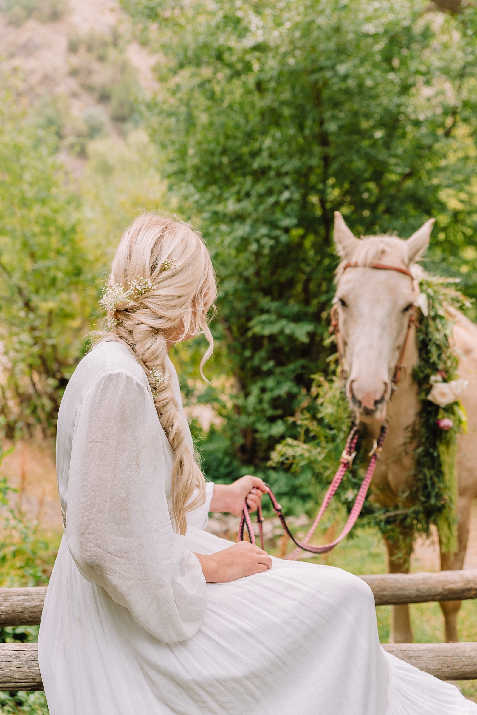 bride sitting on fence with blonde hair braided during styled elopement