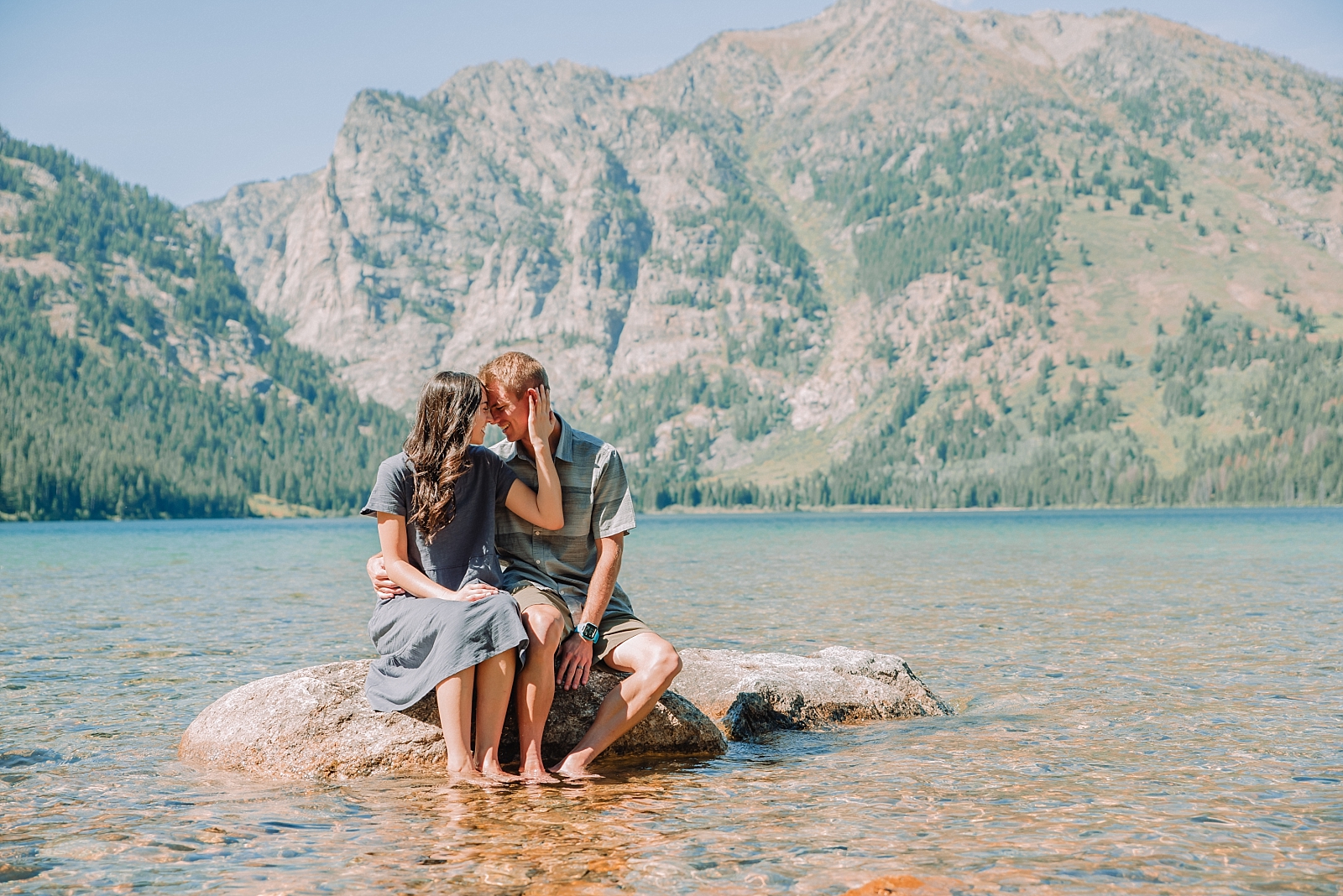 young couple kissing on rock at phelps lake in Tetons National Park
