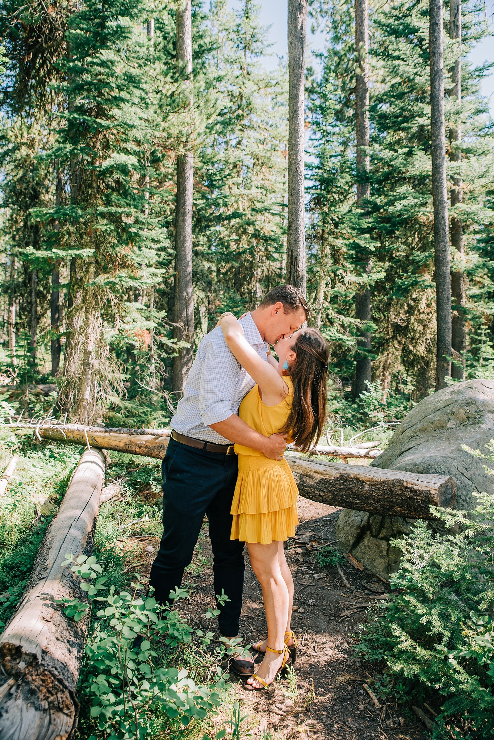 man and woman standing in the woods of Jackson Hole kissing during their honeymoon