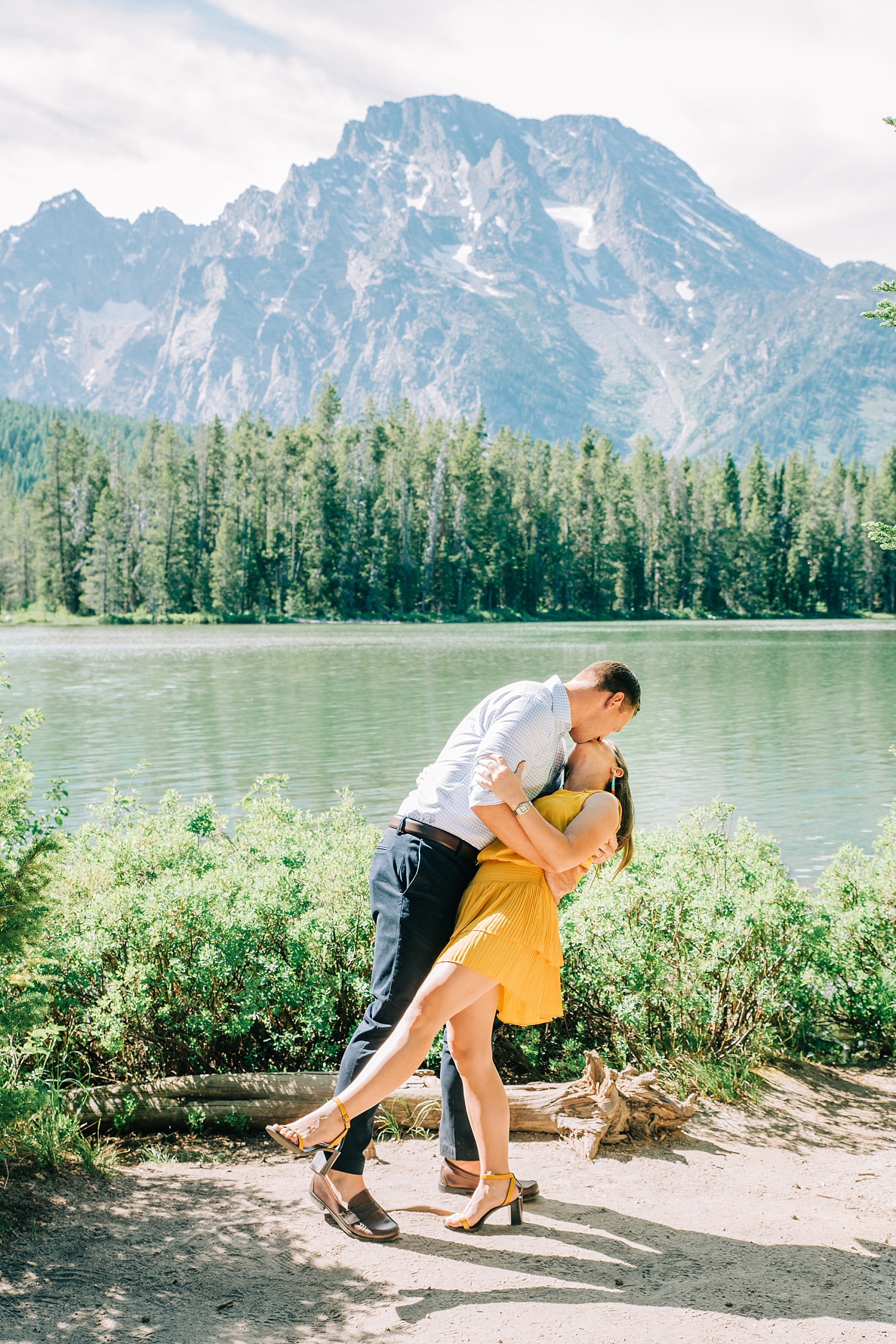 mand dipping his wife back as they dance next to string lake in Jackson Hole with the mountains behind them