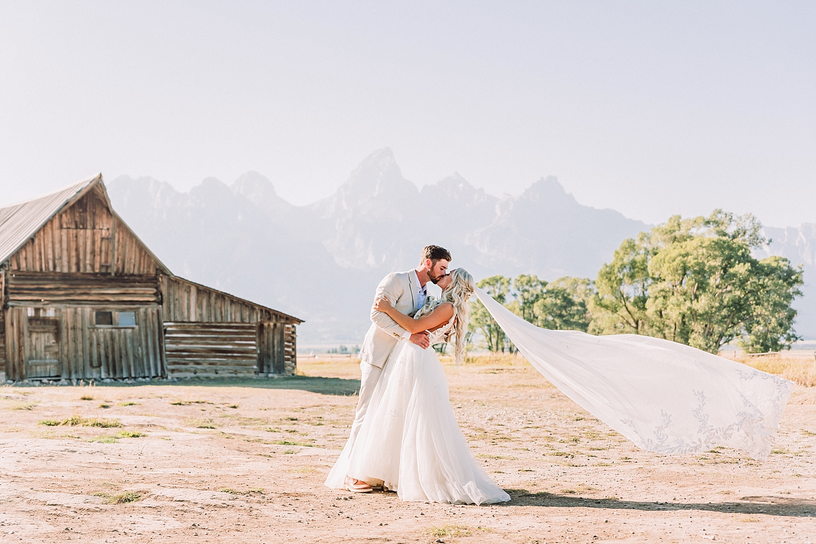 Bride and groom kiss in front of TA Moulton Barn at Mormon Row