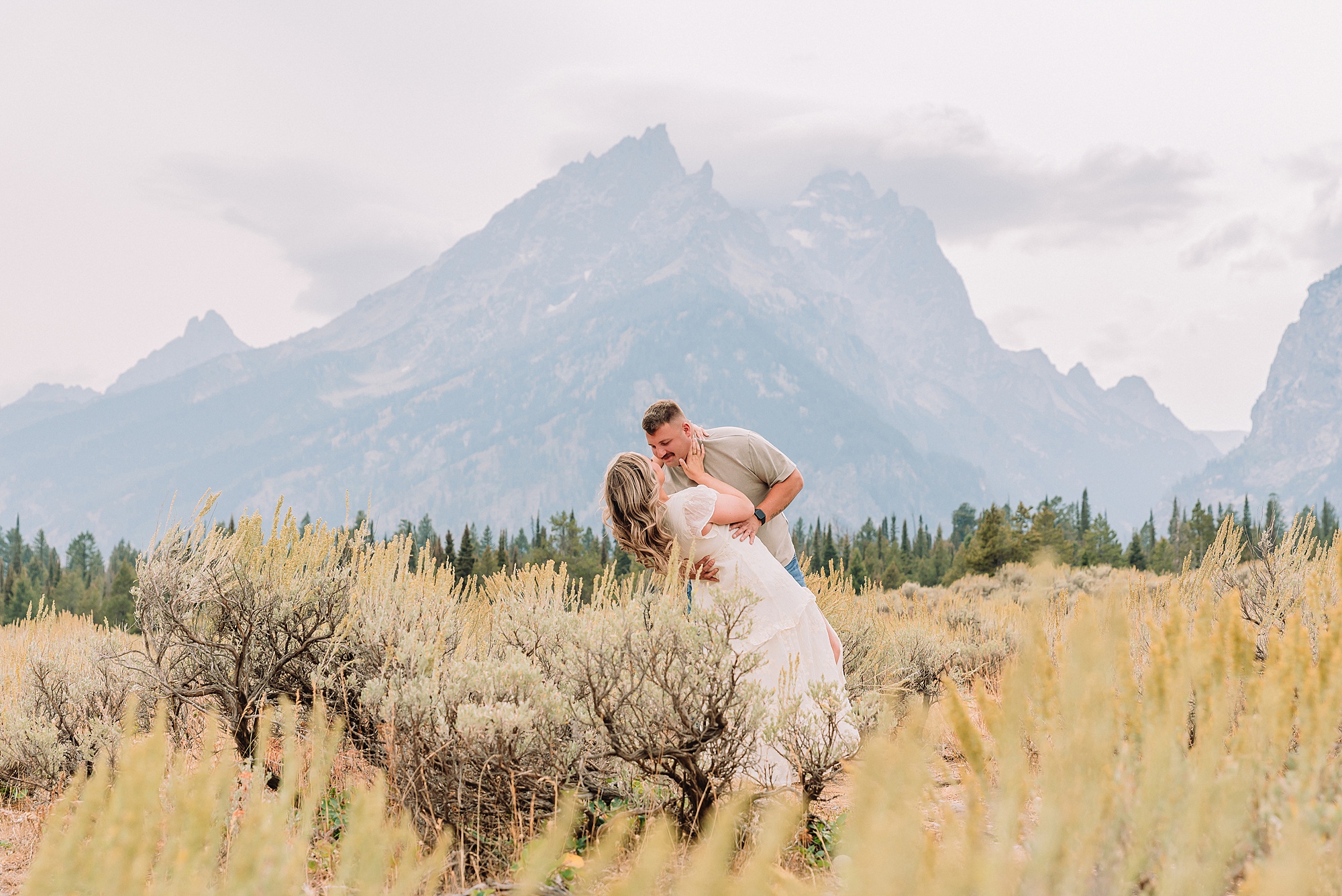 engaged couple stands in front of the Teton Mountains in romantic pose