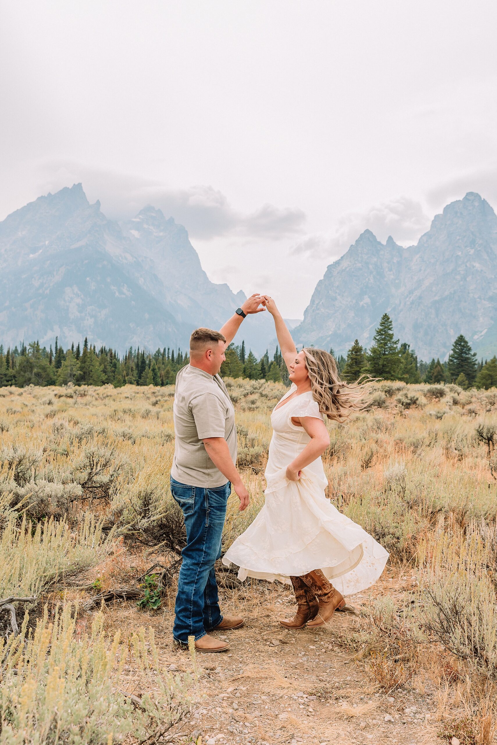 engaged couple stands in front of the Teton Mountains in romantic pose