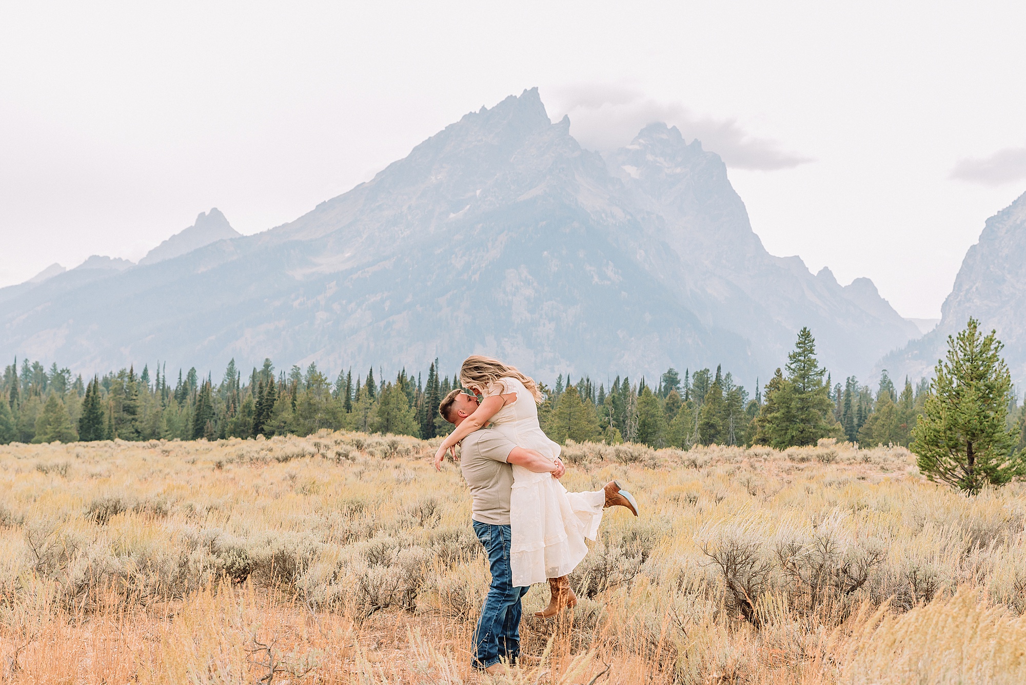 engaged couple stands in front of the Teton Mountains in romantic pose