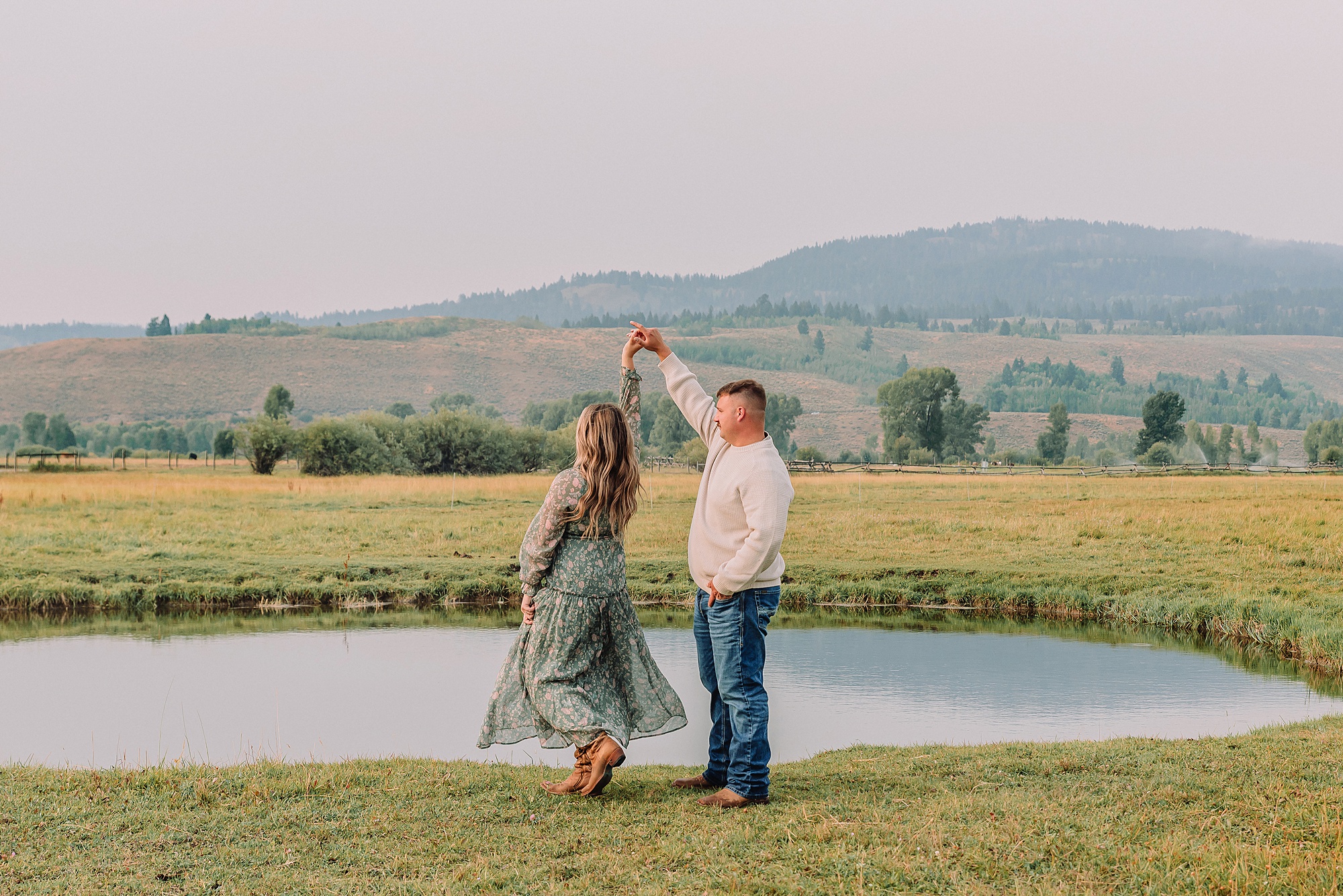 man twirls woman in dress next to a pond at Diamond Cross Ranch