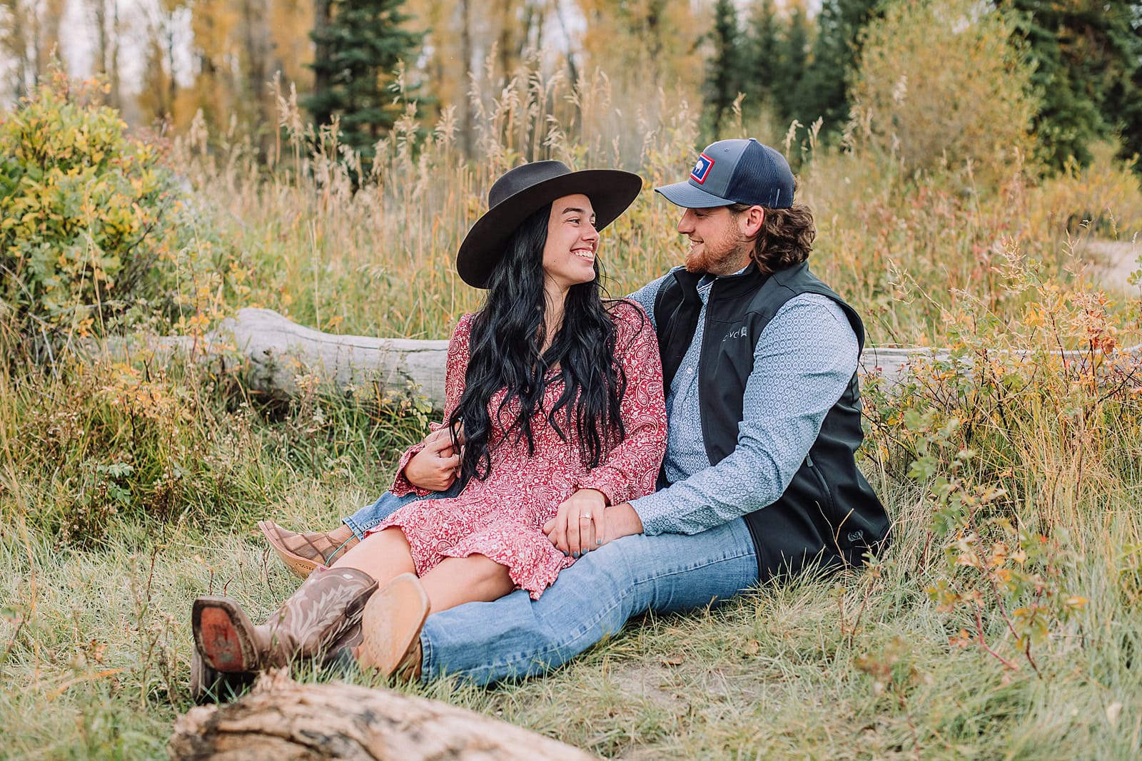 man and woman pose with hats at schwabacher landing during engagement photos