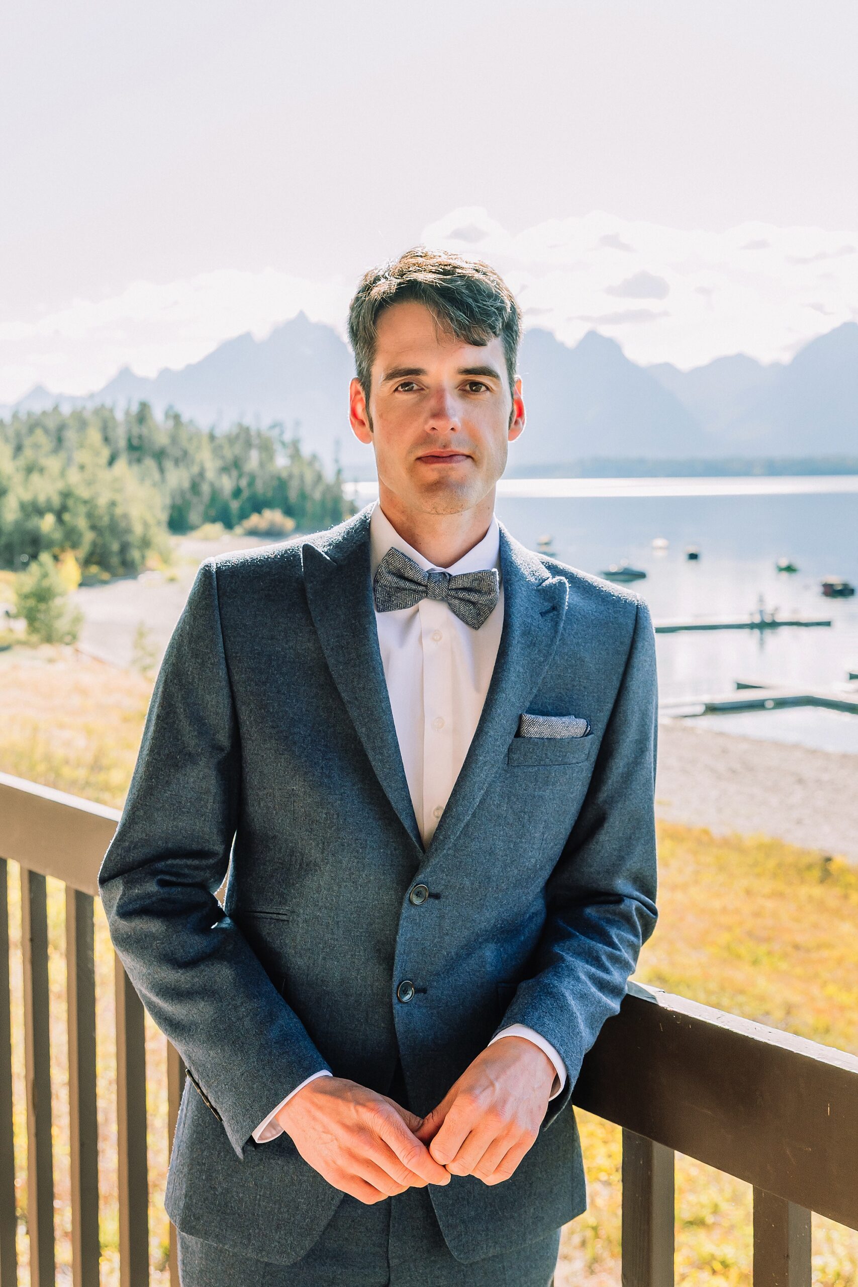 groom poses for a photo at signal mountain lodge with Jackson Lake in the background
