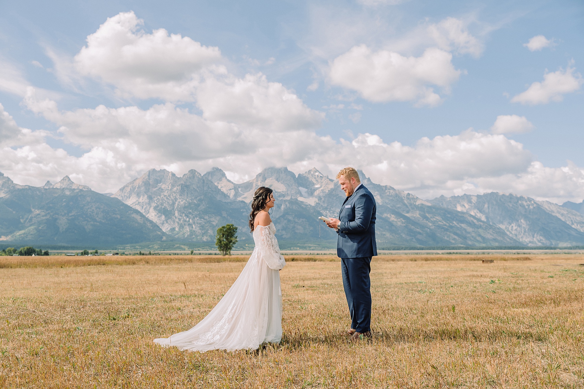 bride and groom share pre-ceremony first look in a field with the Teton mountains behind them