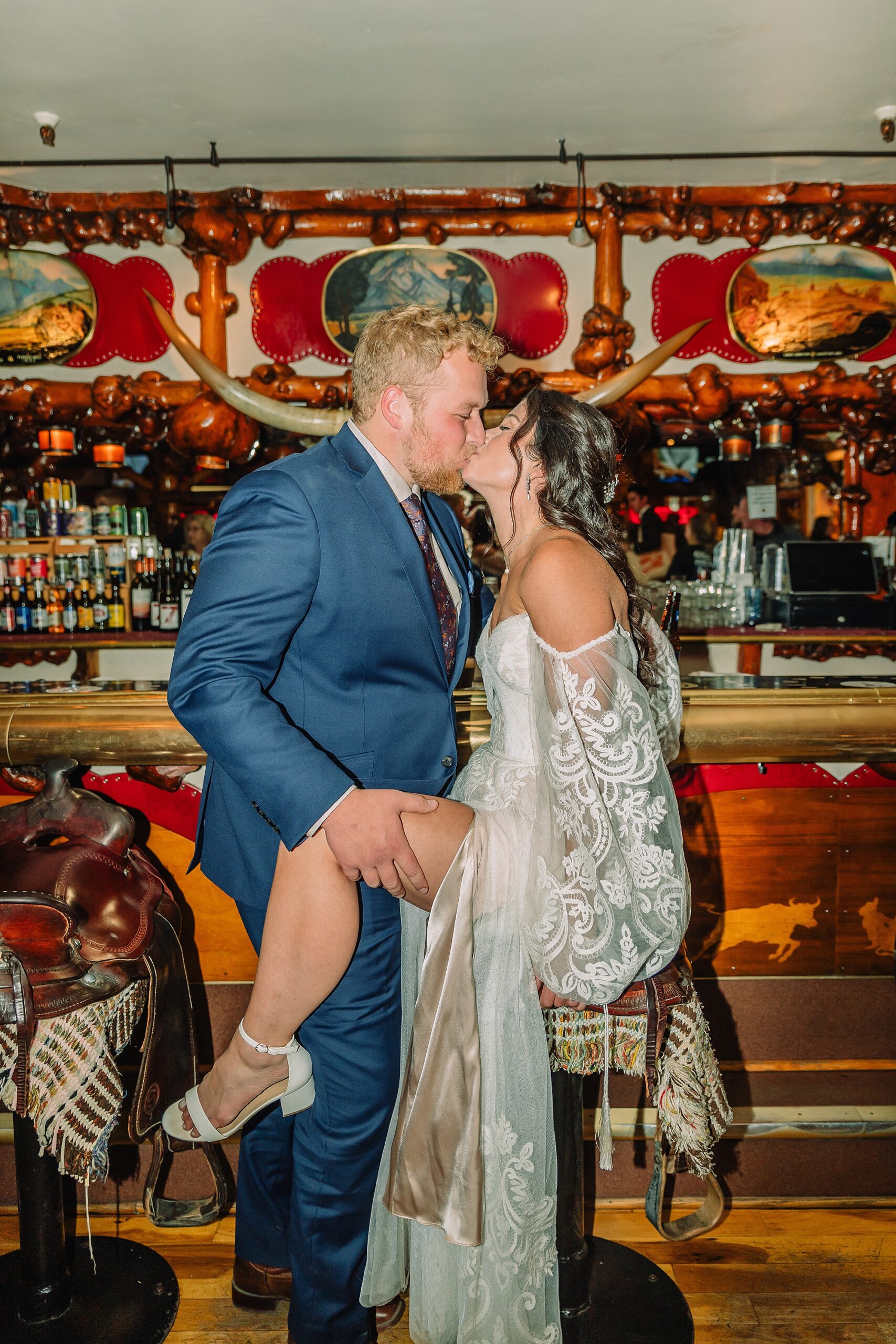 bride and groom share pre-dinner drinks at the million dollar cowboy bar while sitting on saddle chairs