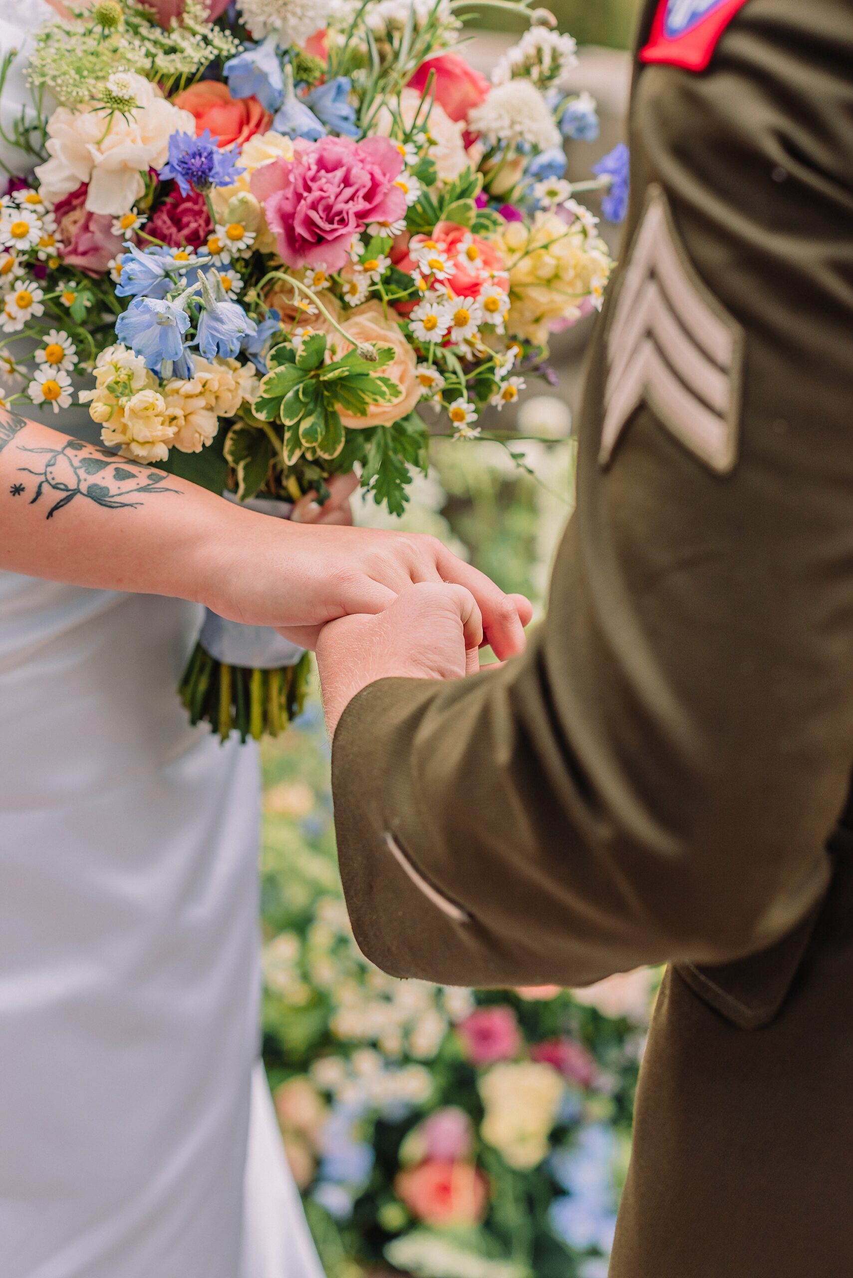 Couple holds hands during wedding ceremony at Snake River Overlook in GTNP, wedding bouquet is highlighted in the framing