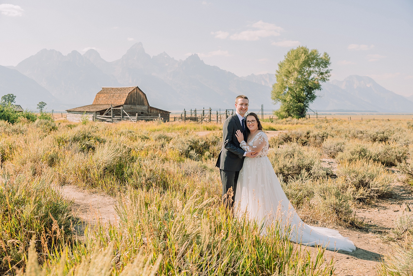 Jackson Hole wedding photographer barn photos Mormon Row western glam wedding dress deep neckline lace details mountain elopement with Teton backdrop intimate Jackson Hole wedding photography