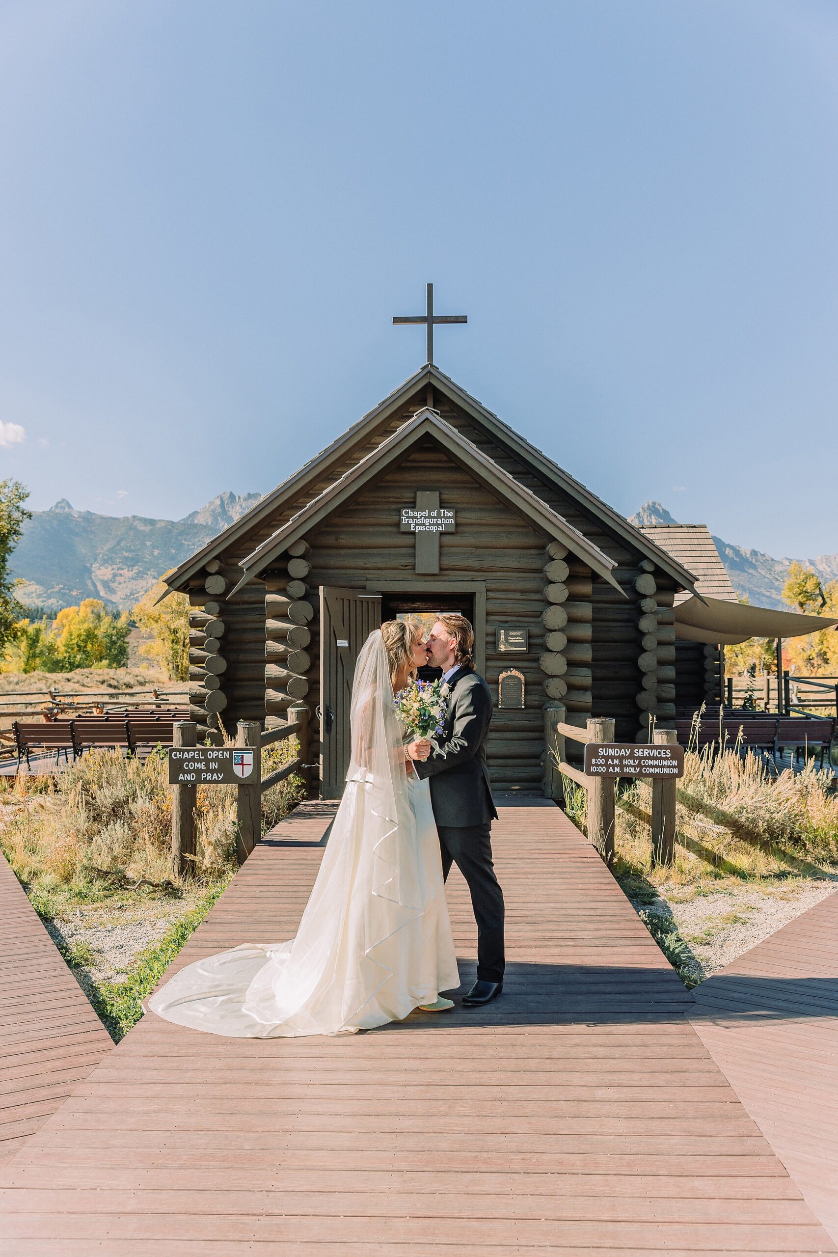 Grand Teton National Park micro wedding Chapel of the Transfiguration bride and groom portraits bride groom cowboy hat bolo tie mountain wedding Chapel of the Transfiguration bell ringing celebration Jackson Hole Wedding Photographers rustic chapel wedding log cabin ceremony