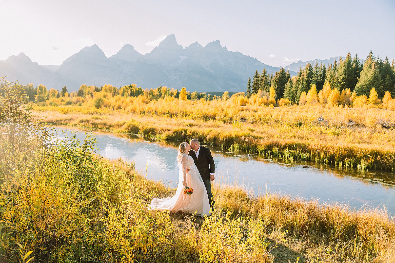 Jackson Hole honeymoon wedding photos Schwabacher Landing wedding portraits Snake River wedding photography September mountain wedding photos beaded wedding dress golden hour western groom style wedding photos Teton mountain wedding portraits sheer cape wedding dress photography