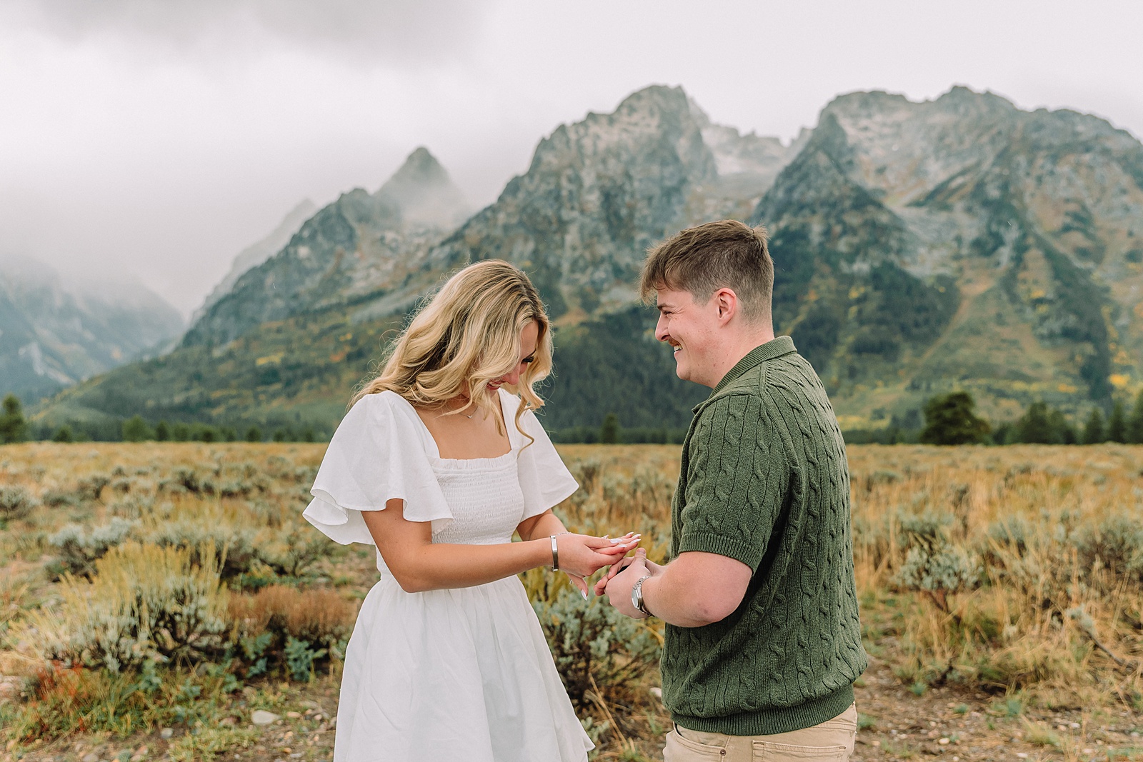 Grand Teton proposal photos at Cathedral View Turnout in the rain Cathedral View Turnout proposal photographer Jackson Hole Wyoming Genuine proposal reaction photos Grand Teton sagebrush field Moody stormy mountain proposal photography Jackson Hole jackson hole proposal photographer