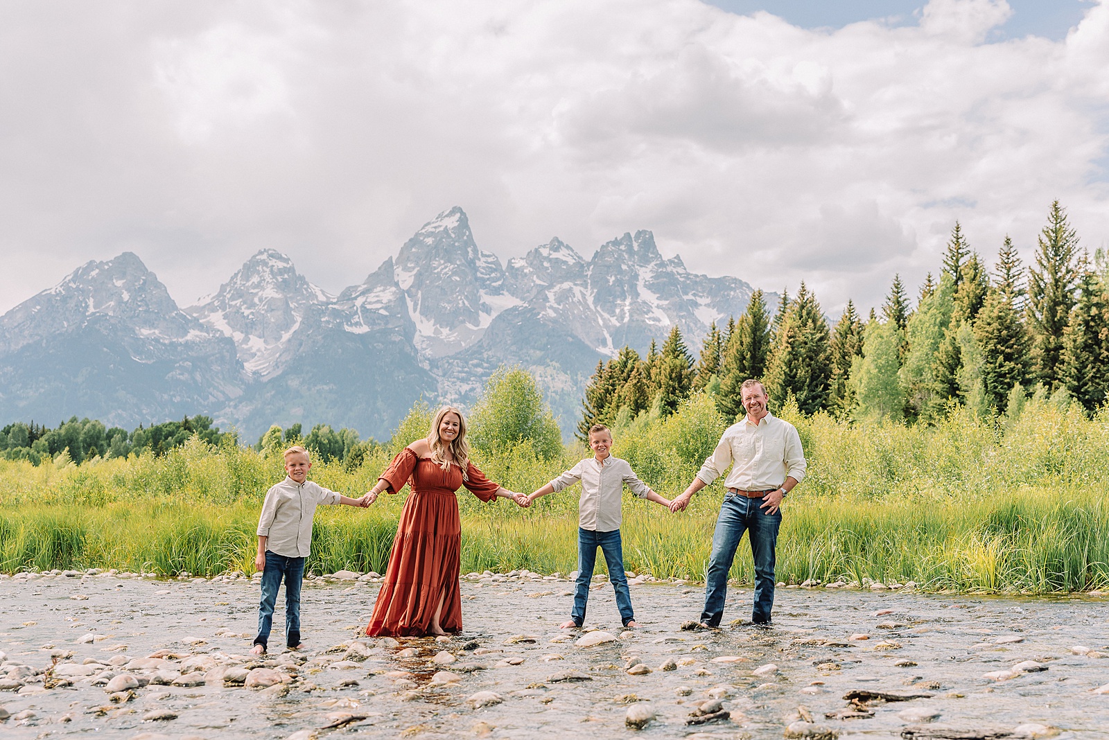 family playing in water during professional photo session Grand Teton sunrise family portraits at Schwabacher Landing cream and rust color palette mountain family photos Grand Teton vacation photographer coordinating family outfits without matching
