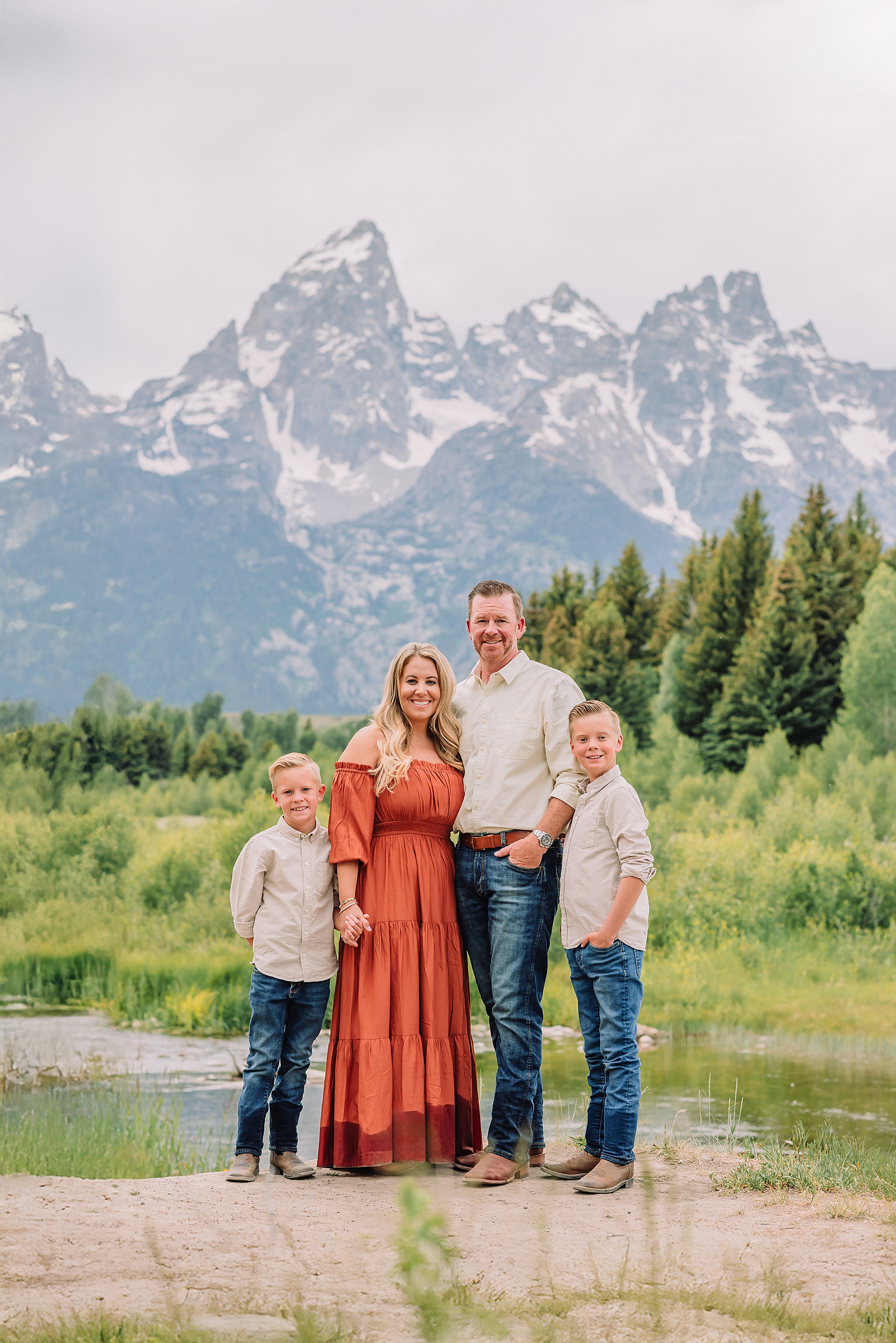 family playing in water during professional photo session Grand Teton sunrise family portraits at Schwabacher Landing cream and rust color palette mountain family photos Grand Teton vacation photographer coordinating family outfits without matching