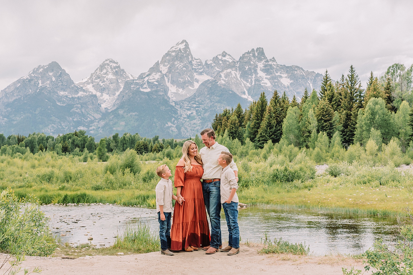 family playing in water during professional photo session Grand Teton sunrise family portraits at Schwabacher Landing cream and rust color palette mountain family photos Grand Teton vacation photographer coordinating family outfits without matching