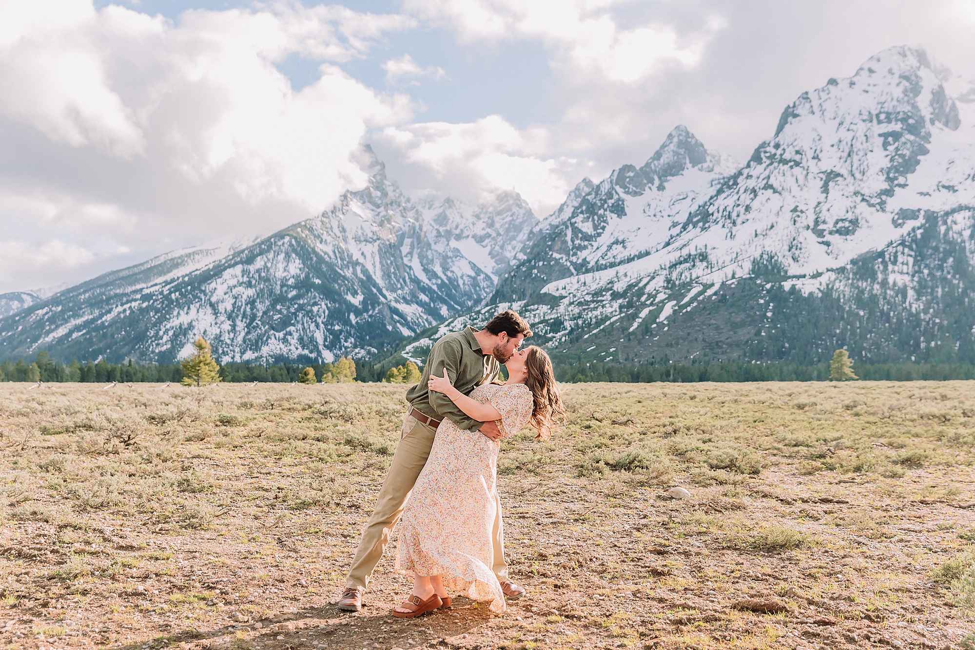 Jackson Hole babymoon maternity photos at Cathedral View Turnout Grand Teton National Park maternity session in spring Cathedral View Turnout couple photos snow capped peaks Flowery maternity dress mountain photography Jackson Hole Jackson Hole Maternity Photographer