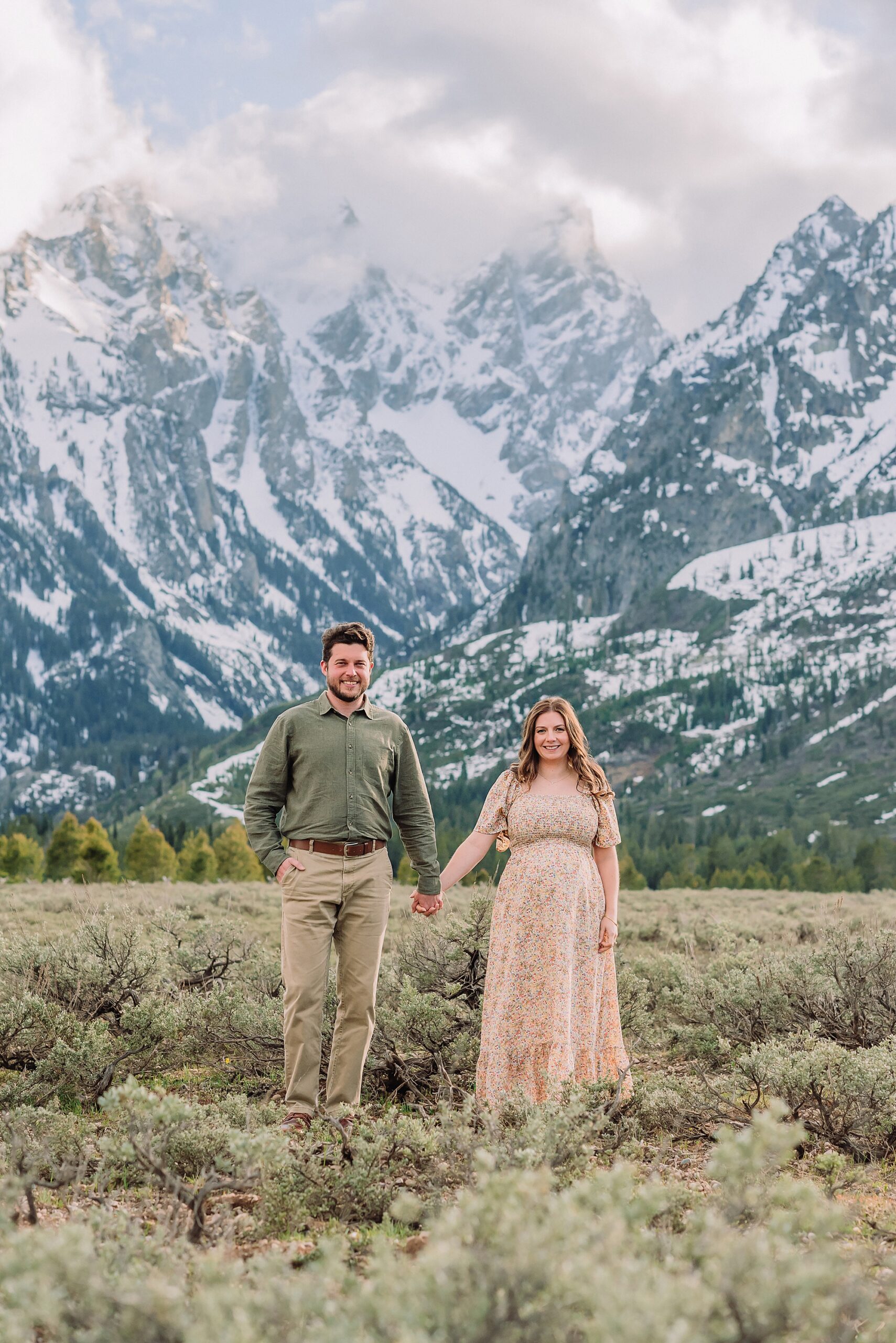 Jackson Hole babymoon maternity photos at Cathedral View Turnout Grand Teton National Park maternity session in spring Cathedral View Turnout couple photos snow capped peaks Flowery maternity dress mountain photography Jackson Hole Jackson Hole Maternity Photographer