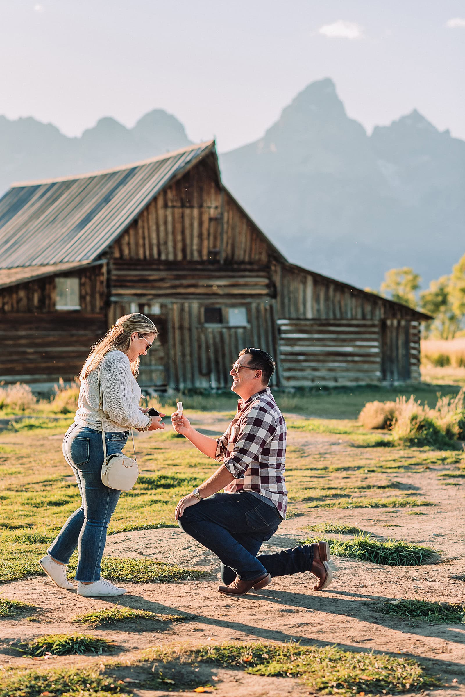 Mormon Row barn proposal photography Jackson Hole Wyoming Sunset engagement photos at TA Moulton Barn Surprise proposal photographer Grand Teton National Park Golden hour mountain proposal photography Jackson Hole Authentic couple portraits Mormon Row historic barn