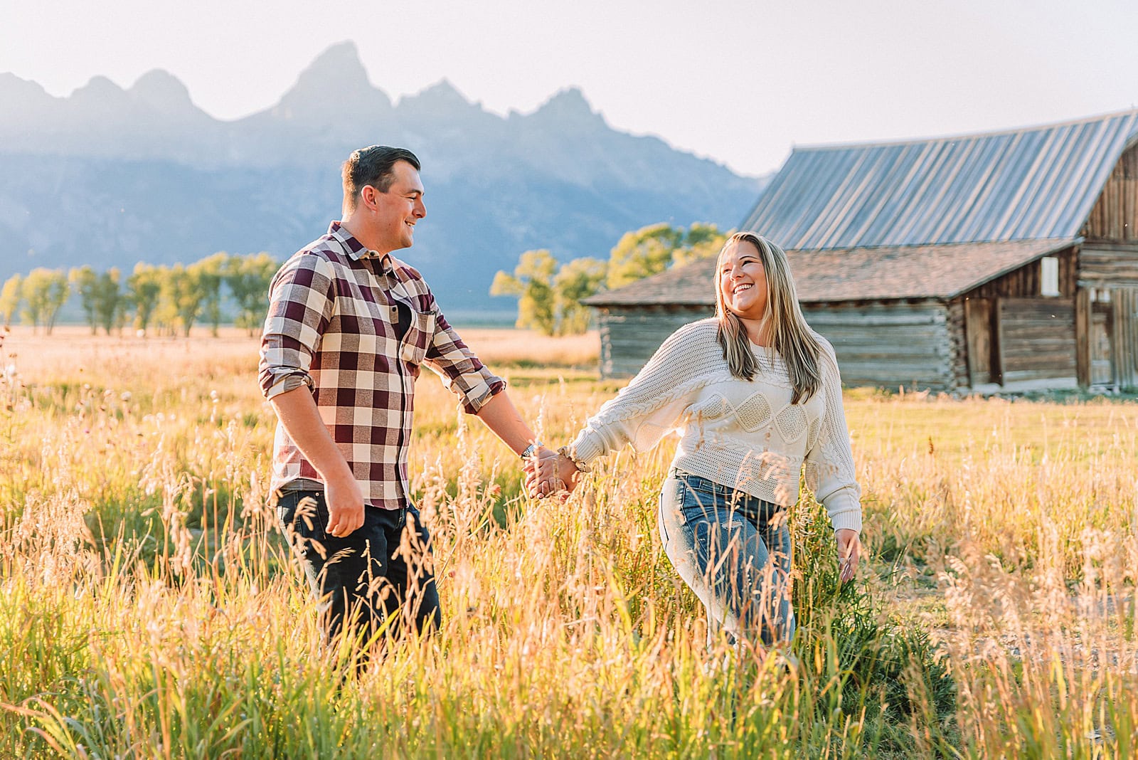 Golden hour mountain proposal photography Jackson Hole Authentic couple portraits Mormon Row historic barn Jackson Hole mountain engagement session summer sunset Candid proposal moment Teton mountain backdrop photography Romantic Wyoming barn proposal photos golden light