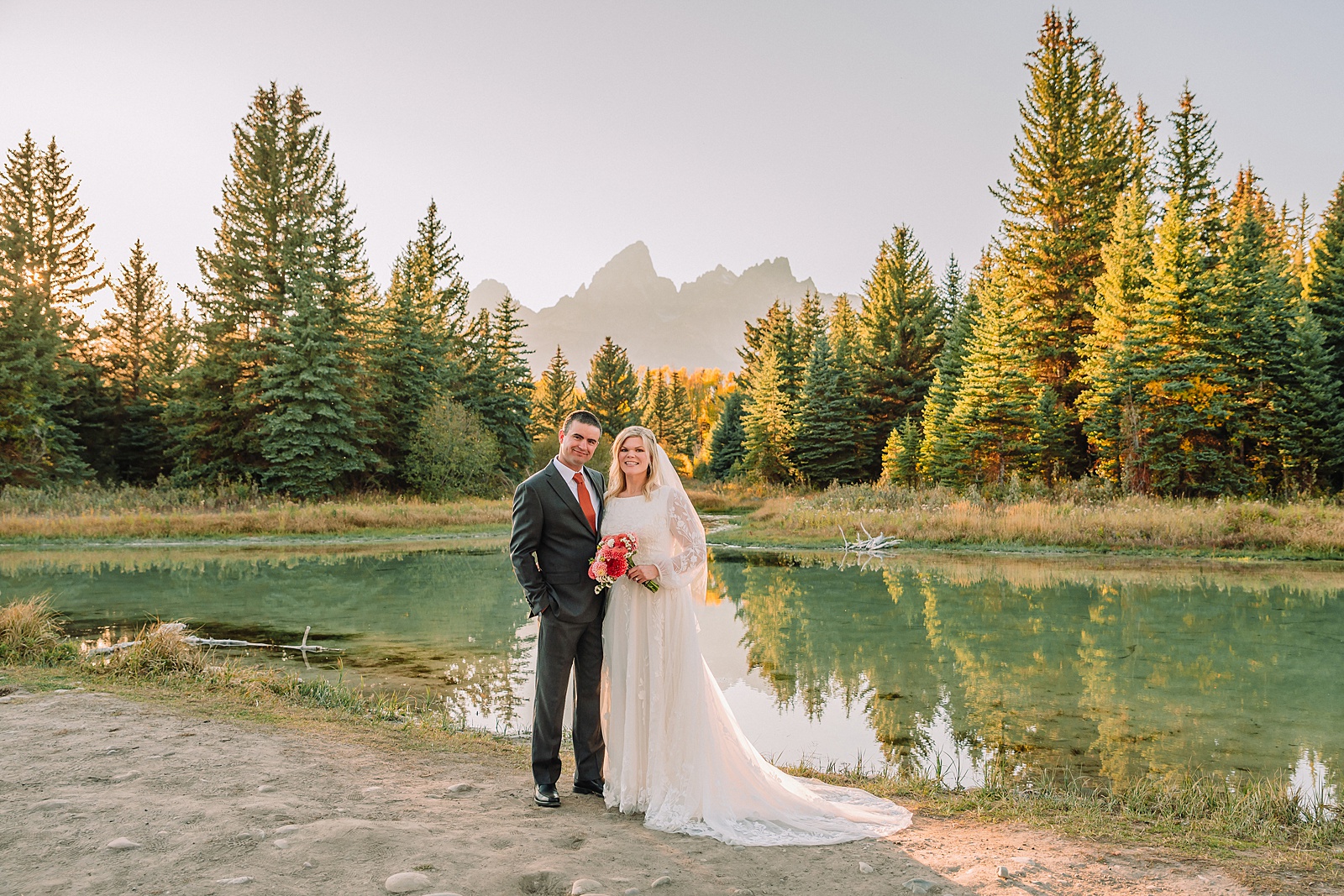 fall bridal portraits at Schwabacher Landing Jackson Hole Grand Teton National Park engagement photos String Lake bride in lace wedding dress with mountain backdrop Wyoming Schwabacher Landing fall color wedding photography Jackson Hole couple portraits with Snake River reflection bride and groom in fall foliage Grand Teton Wyoming rust orange tie groom wedding portraits Jackson Hole fall September engagement photos String Lake Teton National Park