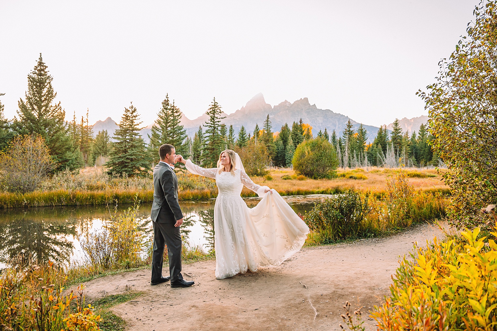 fall bridal portraits at Schwabacher Landing Jackson Hole Grand Teton National Park engagement photos String Lake bride in lace wedding dress with mountain backdrop Wyoming Schwabacher Landing fall color wedding photography Jackson Hole couple portraits with Snake River reflection bride and groom in fall foliage Grand Teton Wyoming rust orange tie groom wedding portraits Jackson Hole fall September engagement photos String Lake Teton National Park