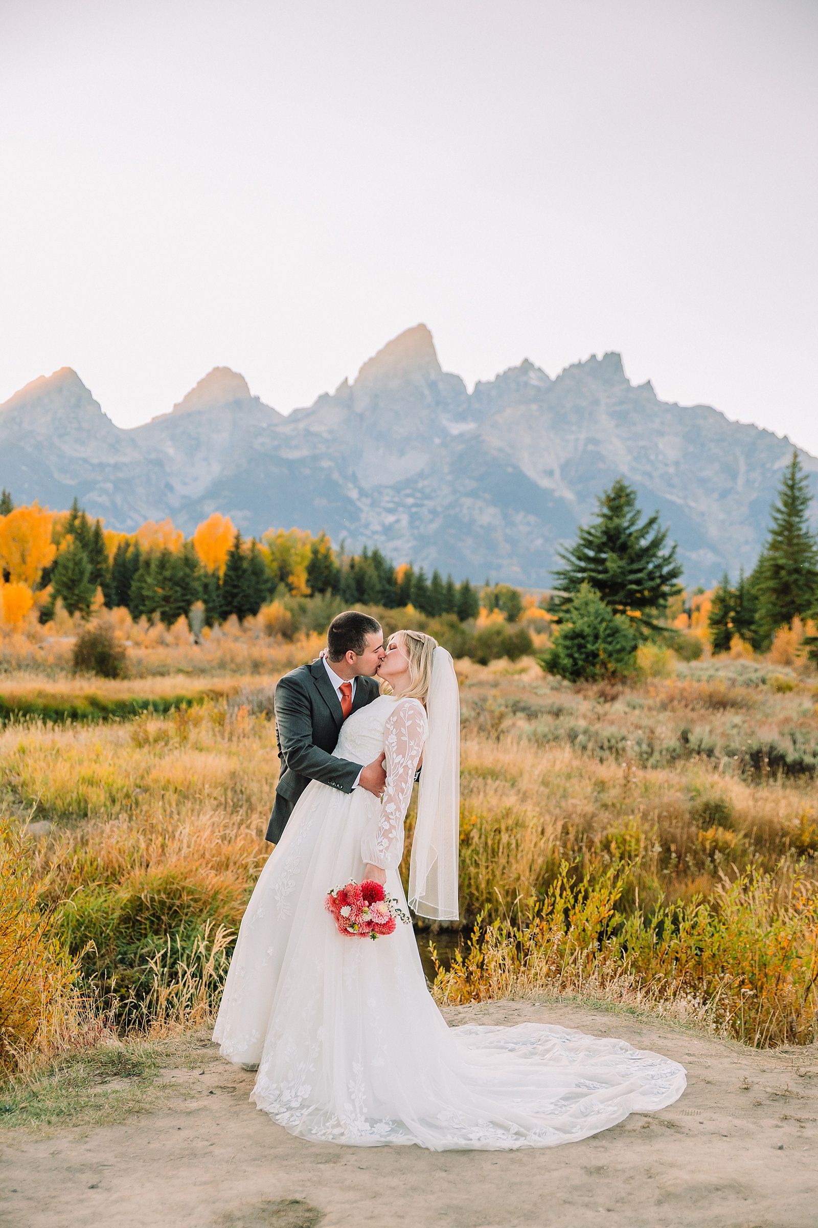 fall bridal portraits at Schwabacher Landing Jackson Hole Grand Teton National Park engagement photos String Lake bride in lace wedding dress with mountain backdrop Wyoming Schwabacher Landing fall color wedding photography Jackson Hole couple portraits with Snake River reflection bride and groom in fall foliage Grand Teton Wyoming rust orange tie groom wedding portraits Jackson Hole fall September engagement photos String Lake Teton National Park