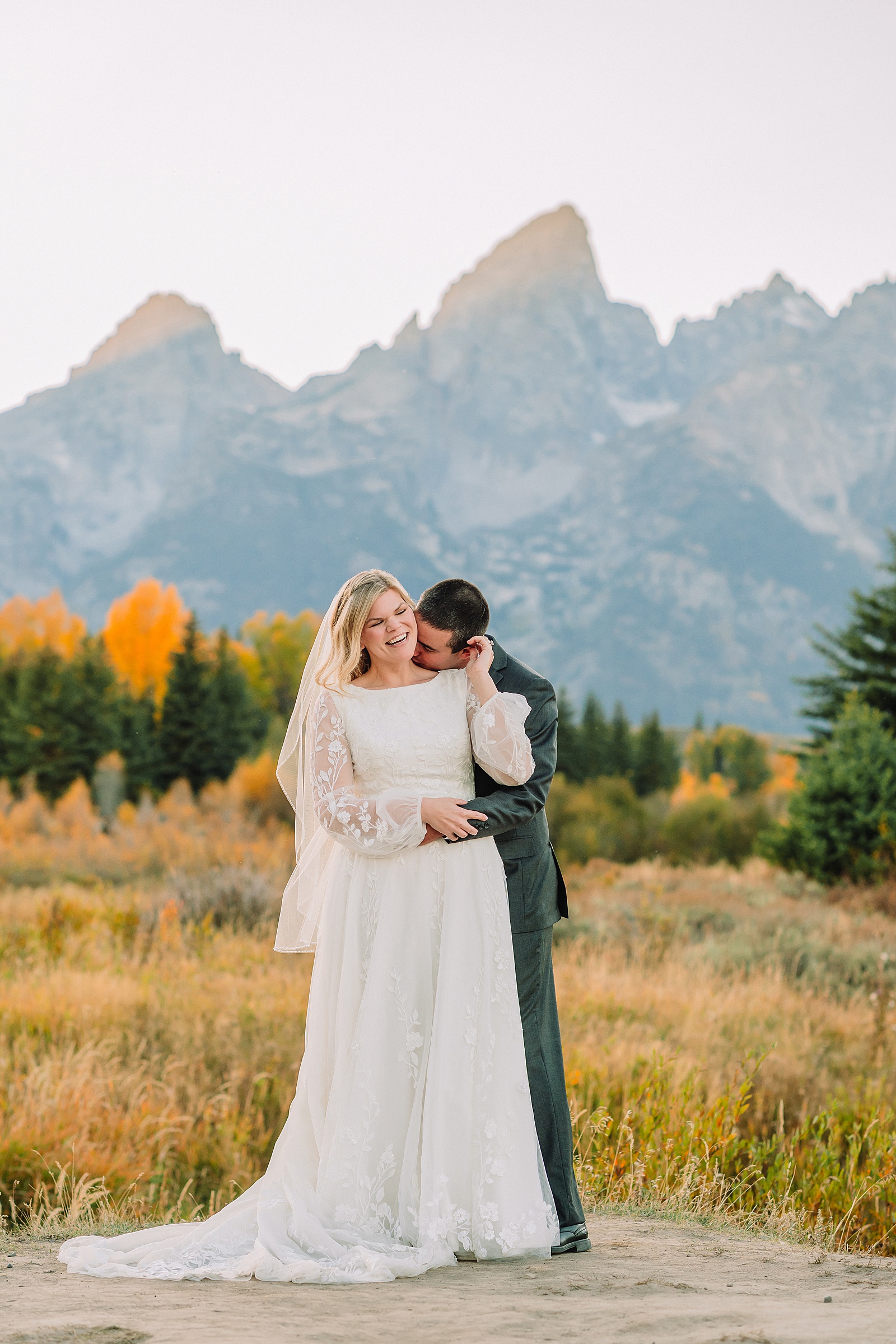 fall bridal portraits at Schwabacher Landing Jackson Hole Grand Teton National Park engagement photos String Lake bride in lace wedding dress with mountain backdrop Wyoming Schwabacher Landing fall color wedding photography Jackson Hole couple portraits with Snake River reflection bride and groom in fall foliage Grand Teton Wyoming rust orange tie groom wedding portraits Jackson Hole fall September engagement photos String Lake Teton National Park