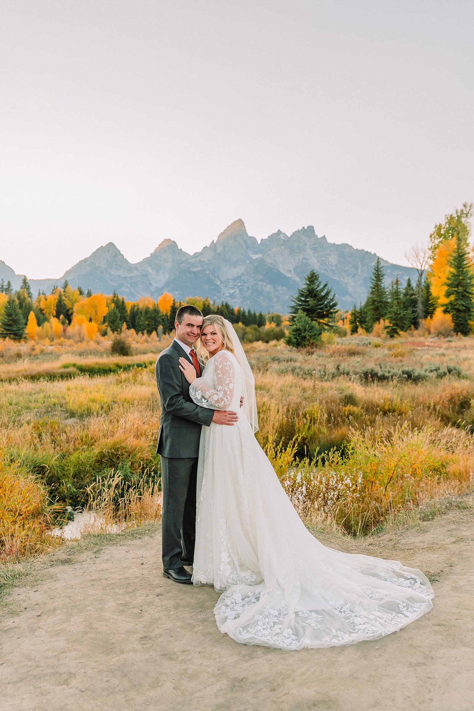 fall bridal portraits at Schwabacher Landing Jackson Hole Grand Teton National Park engagement photos String Lake bride in lace wedding dress with mountain backdrop Wyoming Schwabacher Landing fall color wedding photography Jackson Hole couple portraits with Snake River reflection bride and groom in fall foliage Grand Teton Wyoming rust orange tie groom wedding portraits Jackson Hole fall September engagement photos String Lake Teton National Park