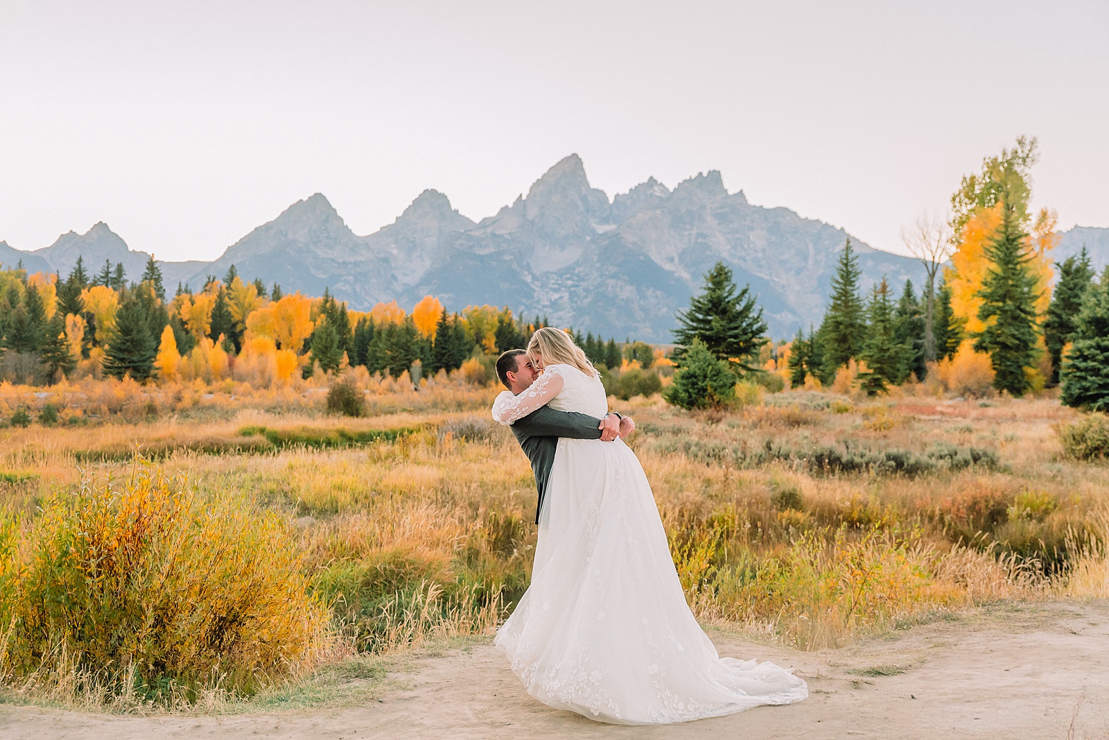 fall bridal portraits at Schwabacher Landing Jackson Hole Grand Teton National Park engagement photos String Lake bride in lace wedding dress with mountain backdrop Wyoming Schwabacher Landing fall color wedding photography Jackson Hole couple portraits with Snake River reflection bride and groom in fall foliage Grand Teton Wyoming rust orange tie groom wedding portraits Jackson Hole fall September engagement photos String Lake Teton National Park