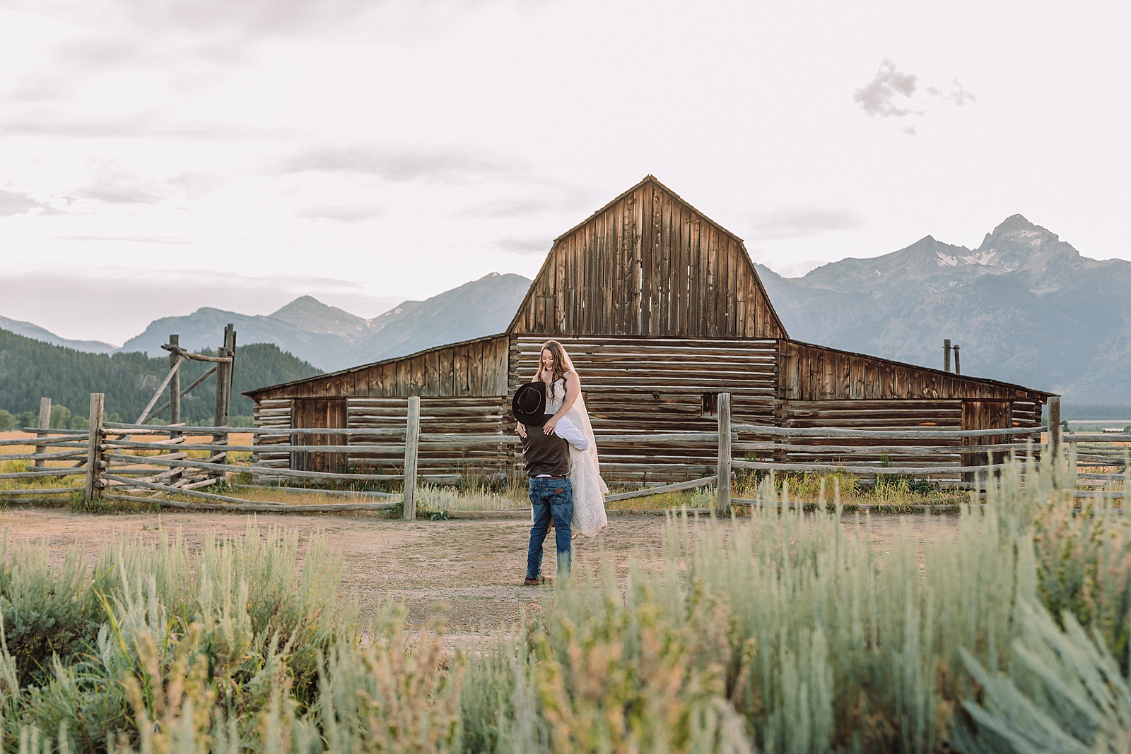 Jackson Hole wedding photographer barn photos Mormon Row western glam wedding dress deep neckline lace details mountain elopement with Teton backdrop intimate Jackson Hole wedding photography
