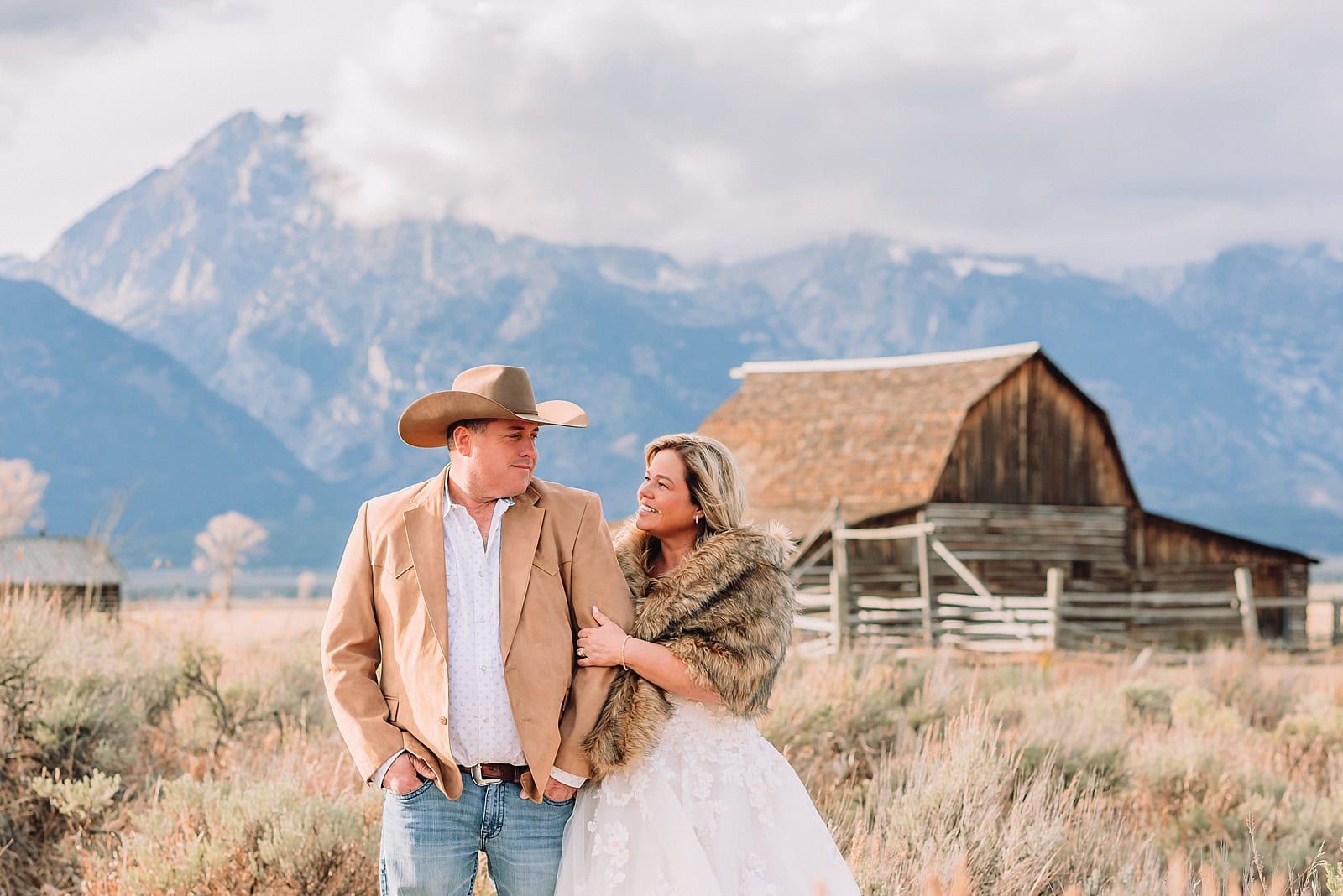 Mormon Row barn elopement photos with Grand Teton mountains fall elopement portraits at Mormon Row historic barns bride in fur wrap at Mormon Row Grand Teton cowboy hat groom Mormon Row wedding photos Schwabacher Landing elopement reflection photos