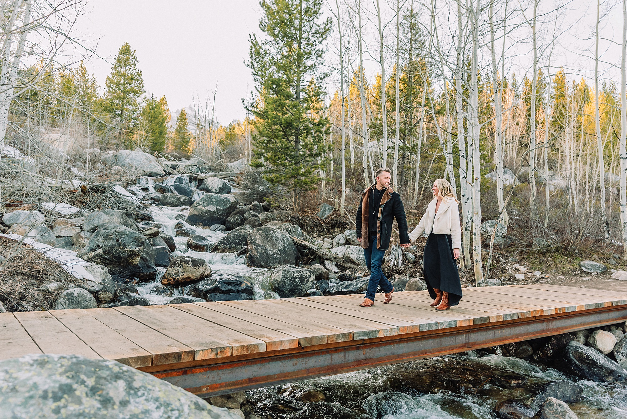 Taggart Lake engagement photography Jackson Hole Wyoming Grand Teton couples anniversary photos spring session Wyoming mountain bridge waterfall couple portraits Luxury western couples photography Jackson Hole Early season mountain engagement photos Tetons