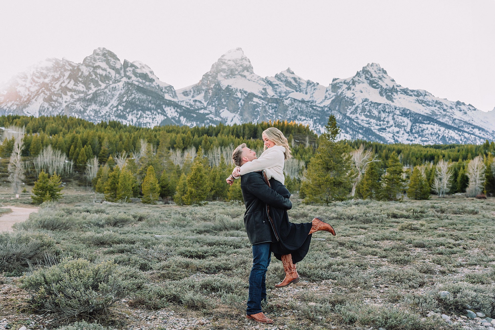 Luxury western couples photography Jackson Hole Early season mountain engagement photos Tetons Taggart Lake trailhead anniversary photography session Cascade bridge couples portraits Grand Teton National Park Faux fur coat mountain couples photoshoot Wyoming