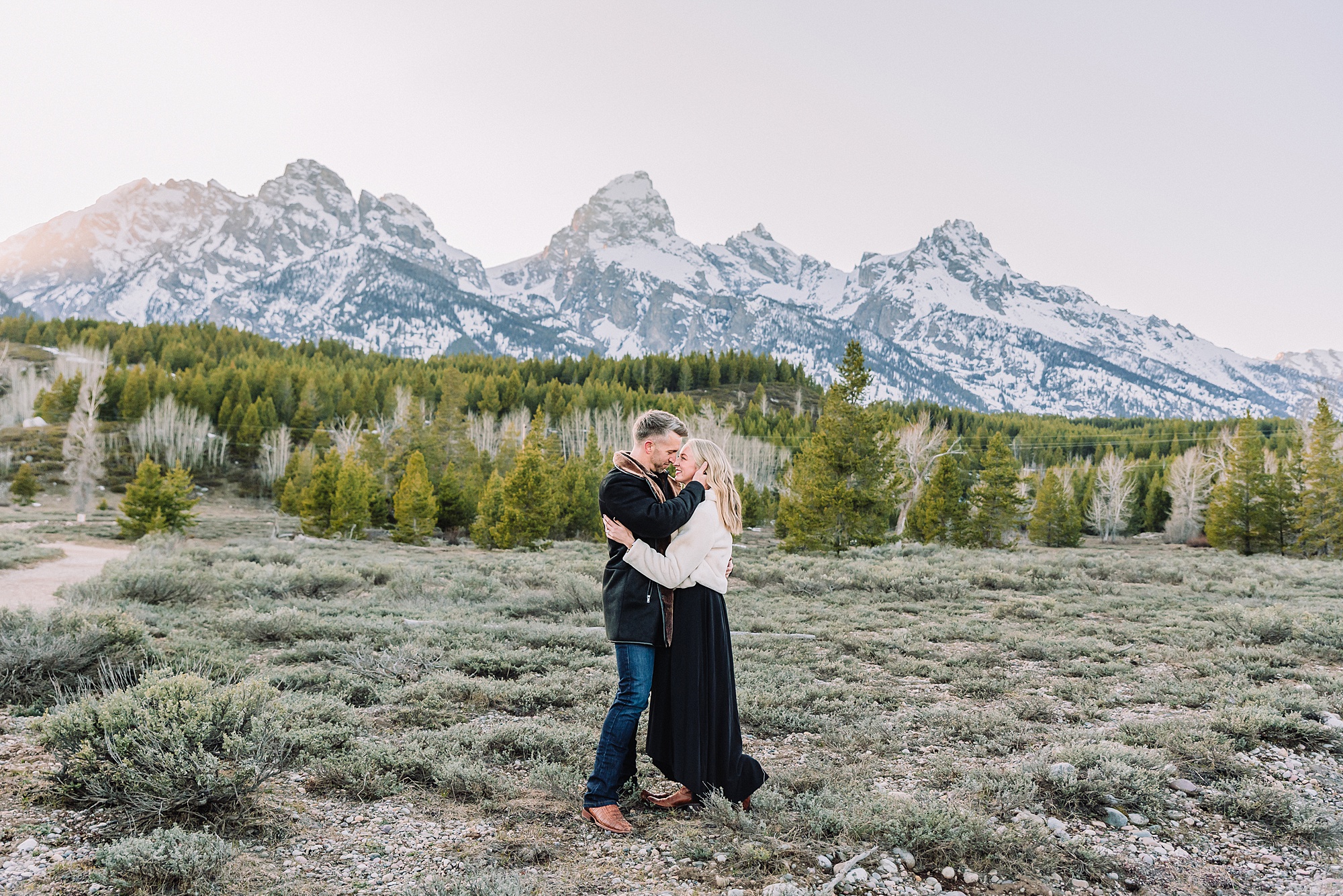 Luxury western couples photography Jackson Hole Early season mountain engagement photos Tetons Taggart Lake trailhead anniversary photography session Cascade bridge couples portraits Grand Teton National Park Faux fur coat mountain couples photoshoot Wyoming