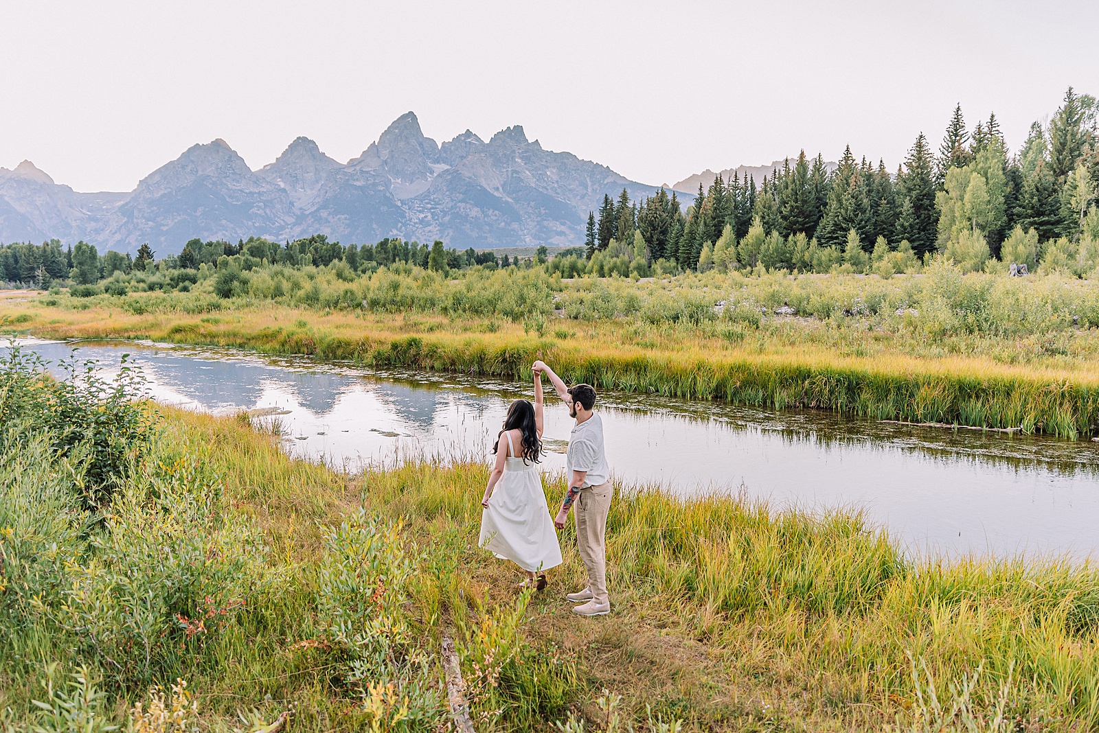 Schwabacher Landing engagement photos Grand Teton National Park white corset dress mountain engagement session Wyoming sunset engagement photos Teton mountain range backdrop couple wearing white outfits Grand Teton engagement shoot Jackson Hole Engagement Photographer