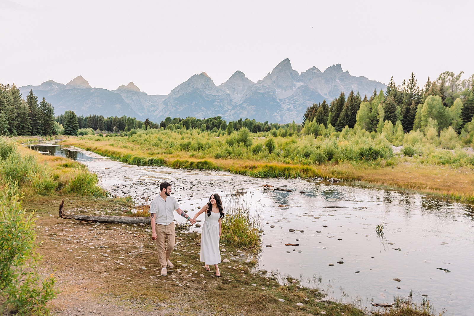 Schwabacher Landing engagement photos Grand Teton National Park white corset dress mountain engagement session Wyoming sunset engagement photos Teton mountain range backdrop couple wearing white outfits Grand Teton engagement shoot Jackson Hole Engagement Photographer