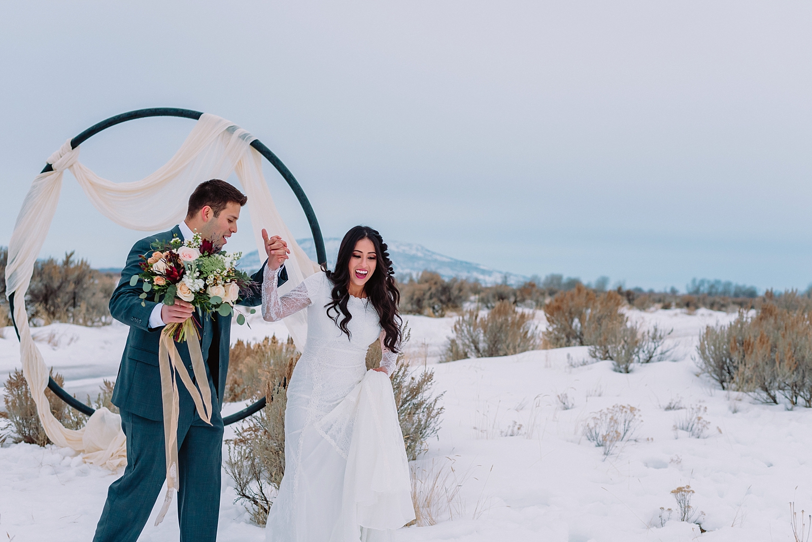 bride and groom walking through snow winter wedding