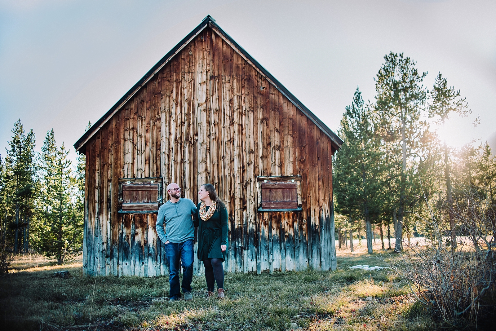 engaged couple in the mountains and woods in front of a wood cabin