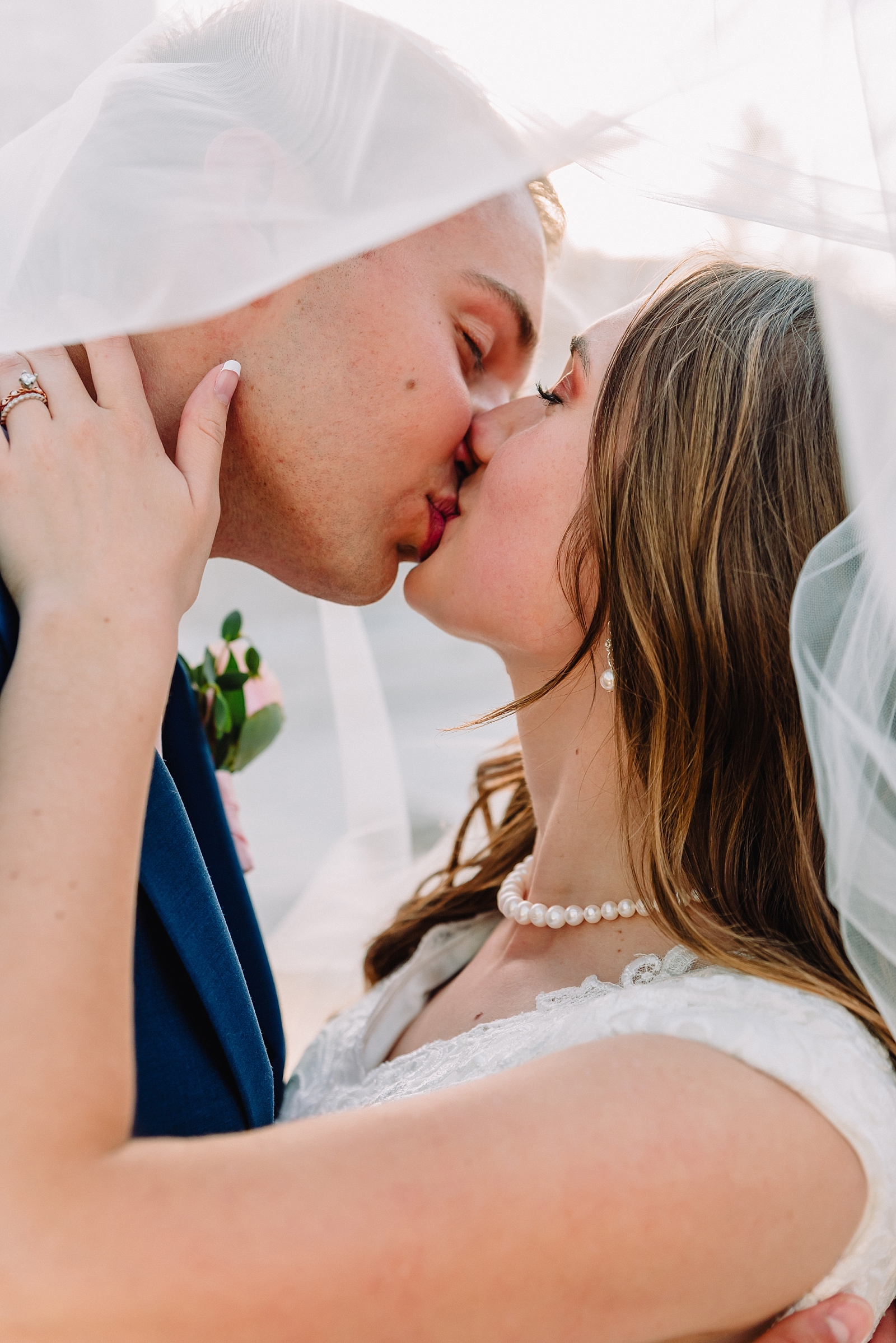 bride and groom kissing under wedding veil