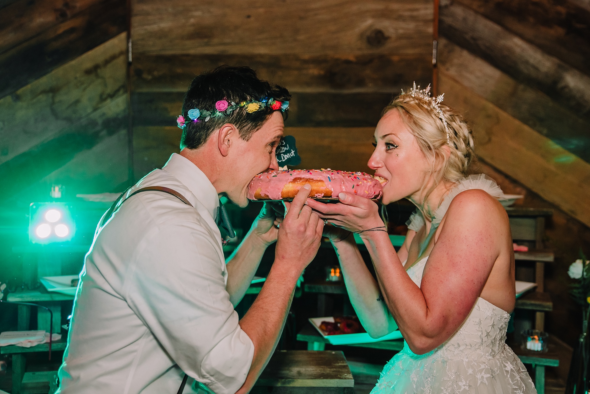 bride and groom eat their pink wedding donut