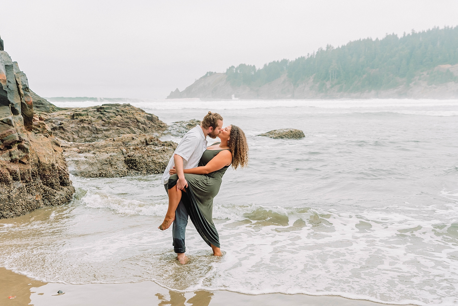 engaged couple playing in the water on Oregon Coast