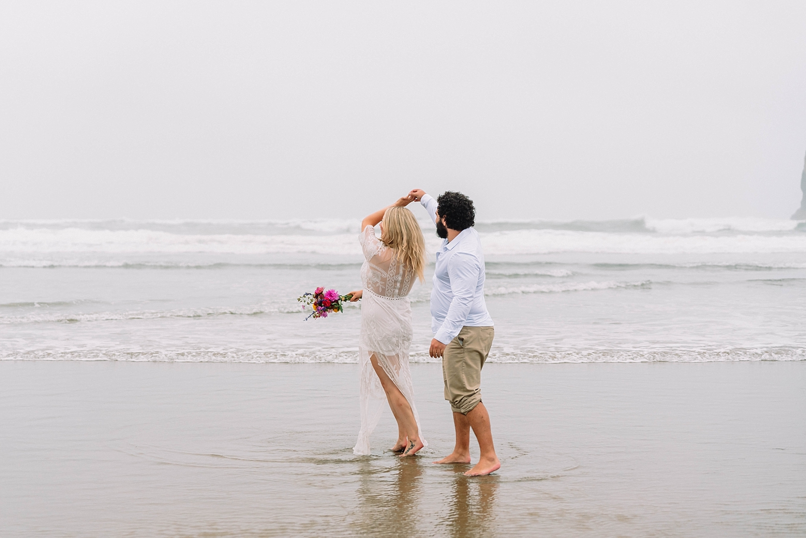 man and woman dancing on oregon coast having brought wedding photographer from home to capture epic beach elopement