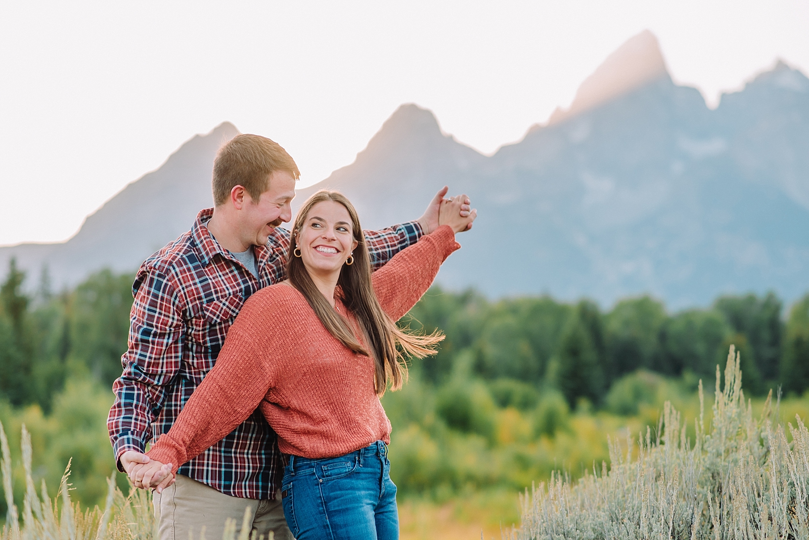 couple holding hands and dancing together at Grand Teton National Park using fall outfit inspiration