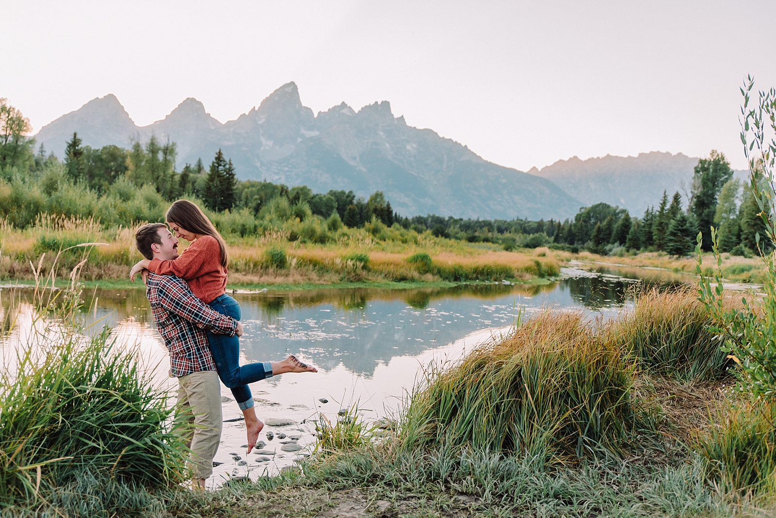 man lifting woman up after proposal at Grand Teton National Park